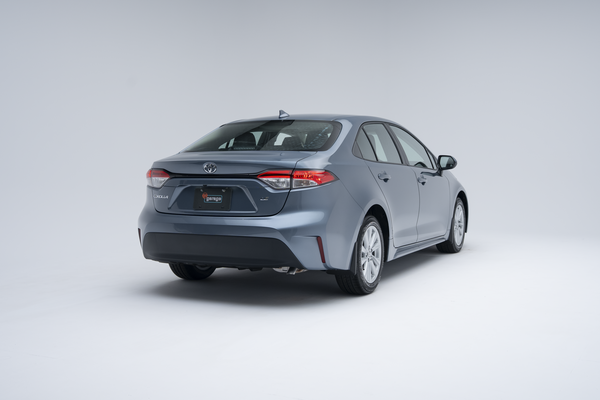 Rear three-quarter view of a light blue 2026 Toyota Corolla sedan on a white studio background.
