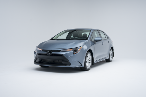 Front three-quarter view of a light blue 2026 Toyota Corolla sedan on a white studio background.