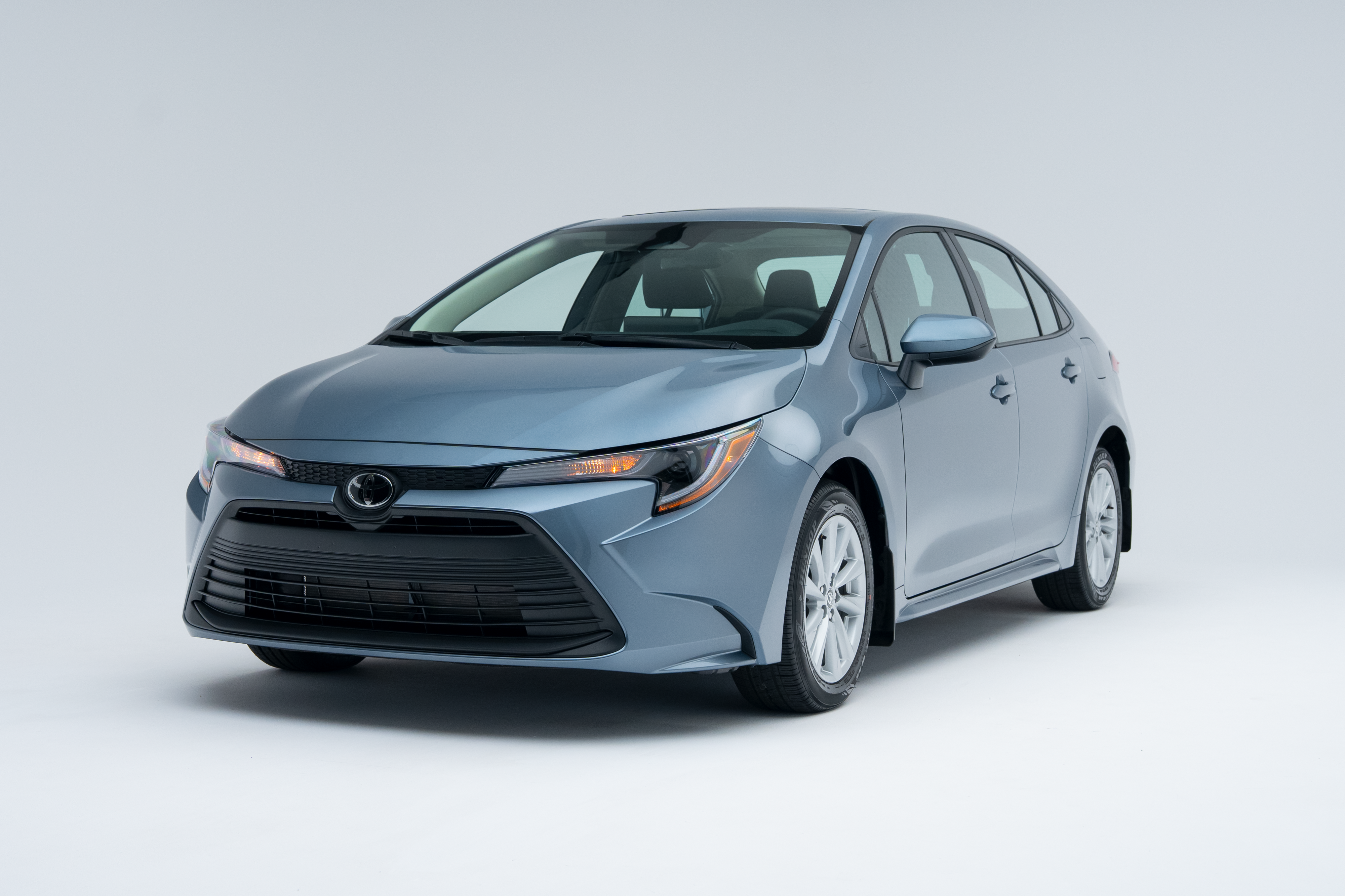 Front three-quarter view of a light blue 2026 Toyota Corolla sedan on a white studio background.