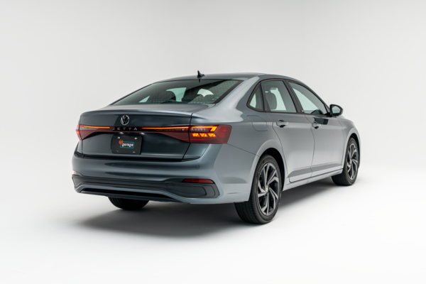 Rear three-quarter view of a grey 2026 Volkswagen Jetta showing LED taillights, alloy wheels and sedan profile.