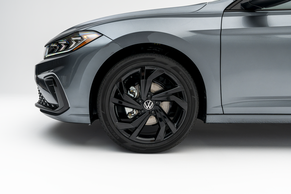 2026 Volkswagen Jetta in gray, featuring a close-up of the front wheel with black alloy rim and Volkswagen logo.