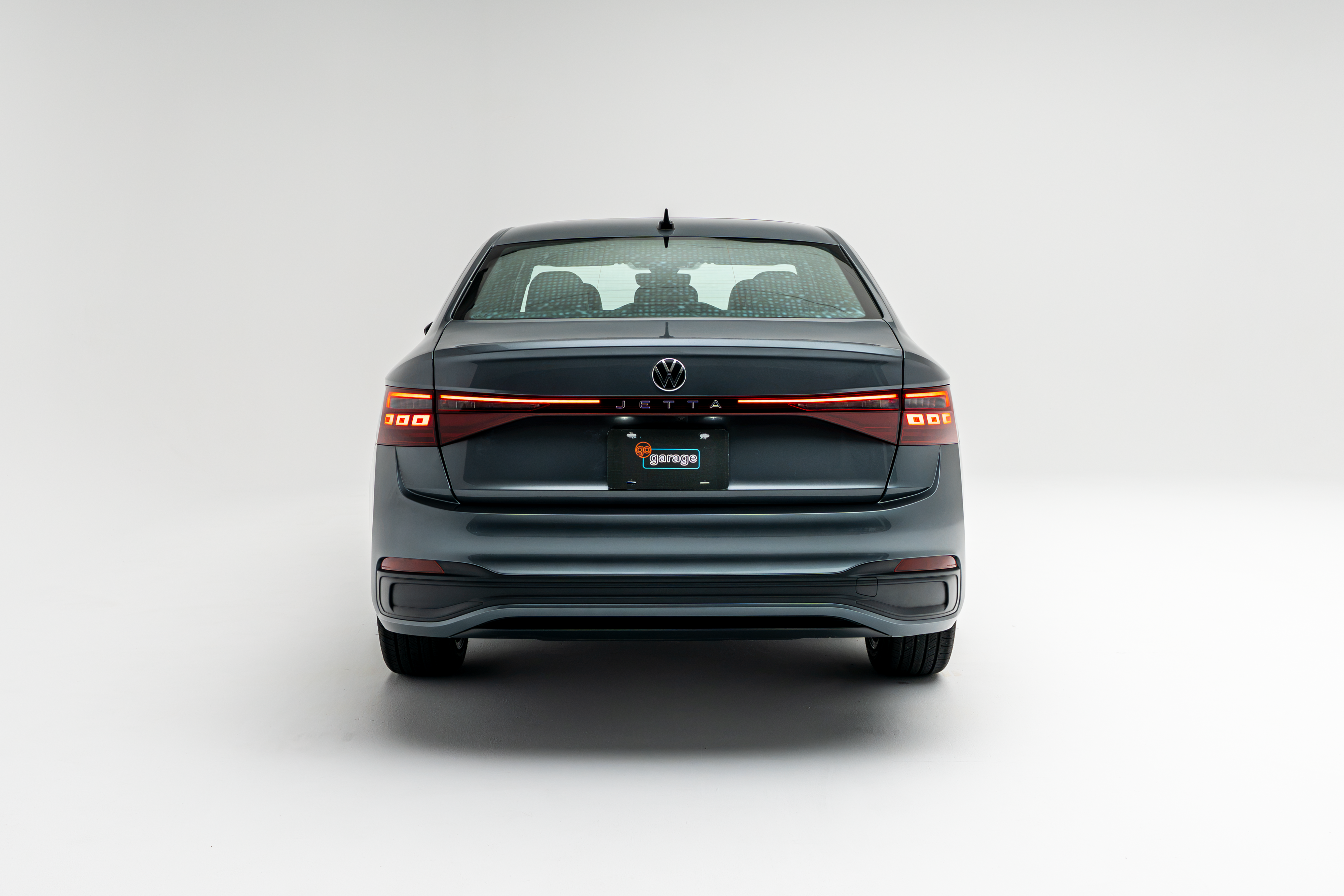 2026 Volkswagen Jetta in gray, shown from the rear with illuminated LED taillights on a white background.