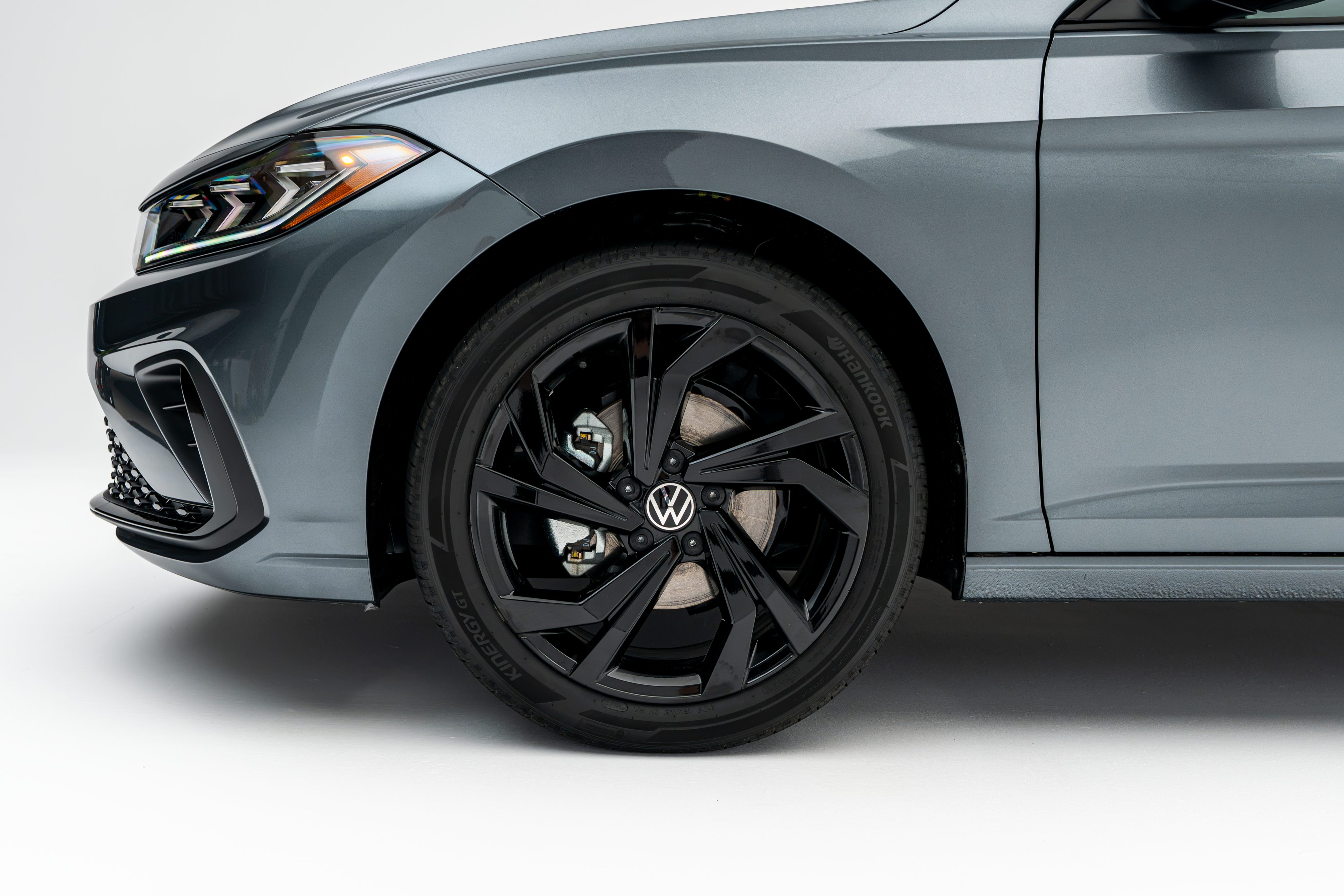 2026 Volkswagen Jetta in gray, featuring a close-up of the front wheel with black alloy rim and Volkswagen logo.