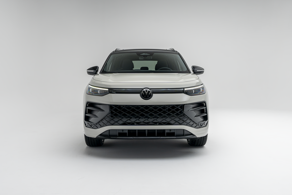 Front view of a white 2026 Volkswagen Tiguan SUV with LED headlights illuminated on a white studio background.