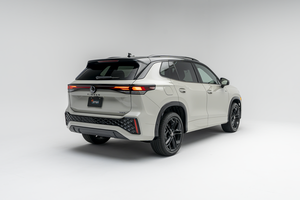 Rear three-quarter view of a white 2026 Volkswagen Tiguan SUV with LED taillights illuminated on a white studio background.