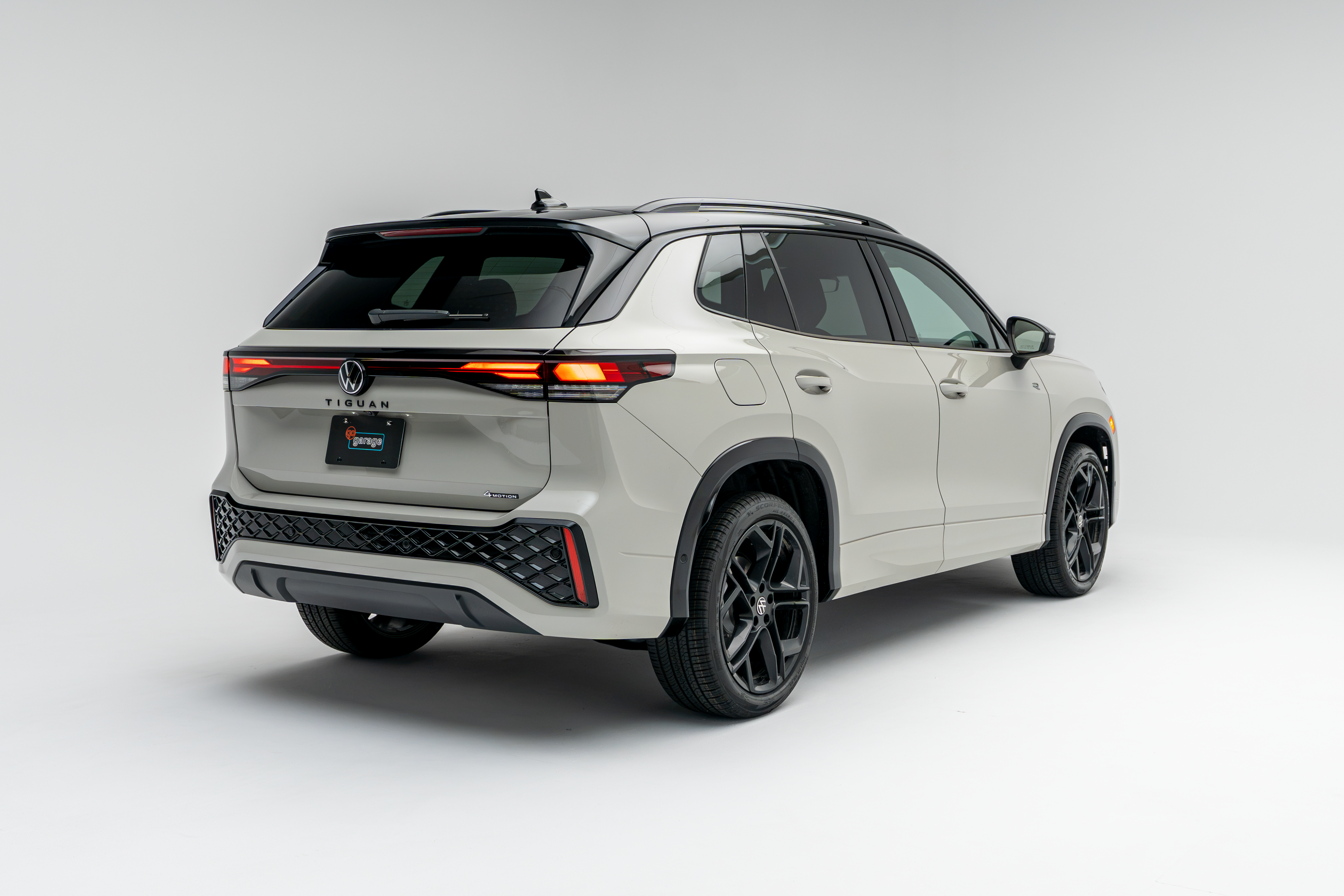 Rear three-quarter view of a white 2026 Volkswagen Tiguan SUV with LED taillights illuminated on a white studio background.