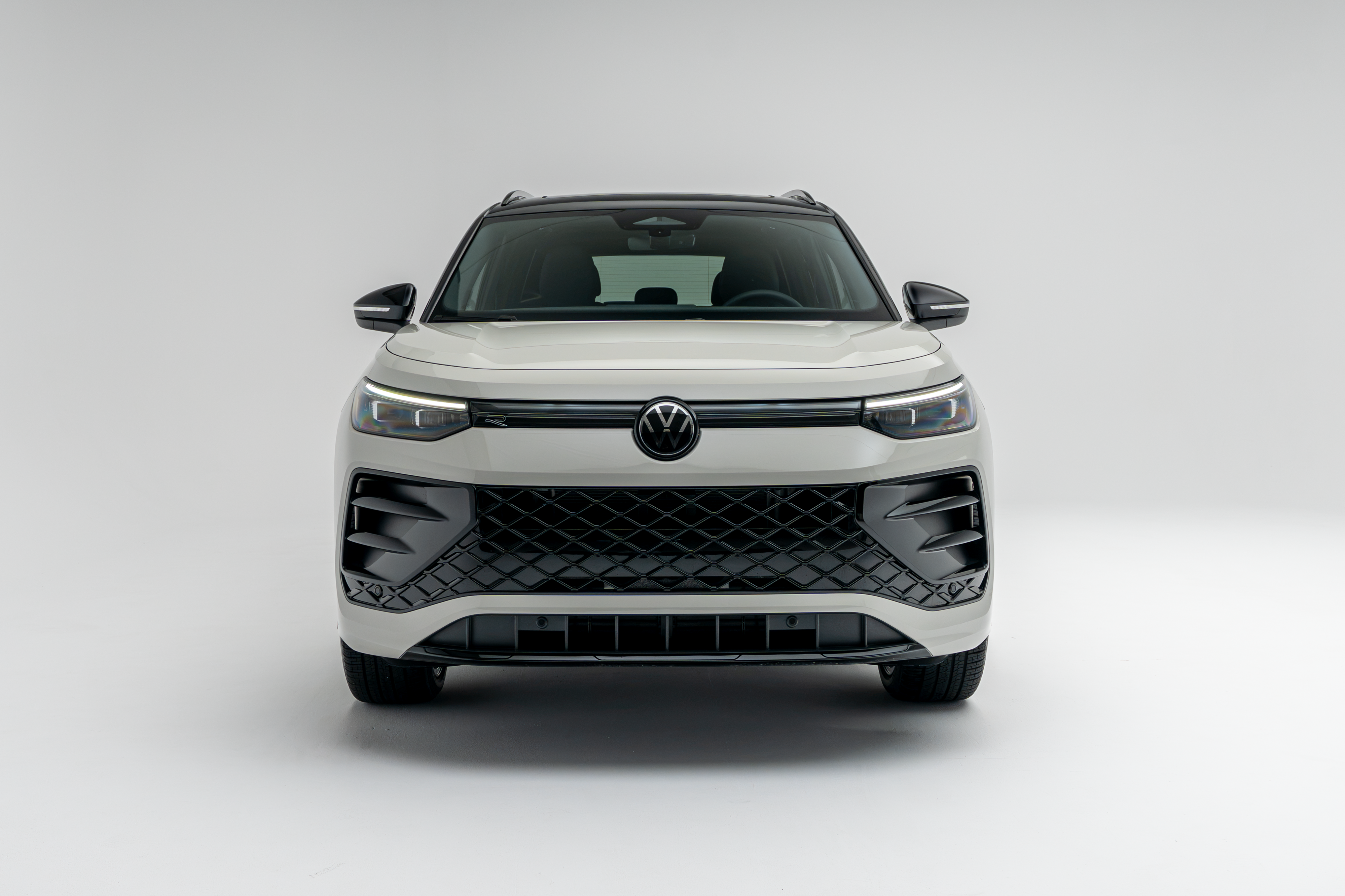 Front view of a white 2026 Volkswagen Tiguan SUV with LED headlights illuminated on a white studio background.