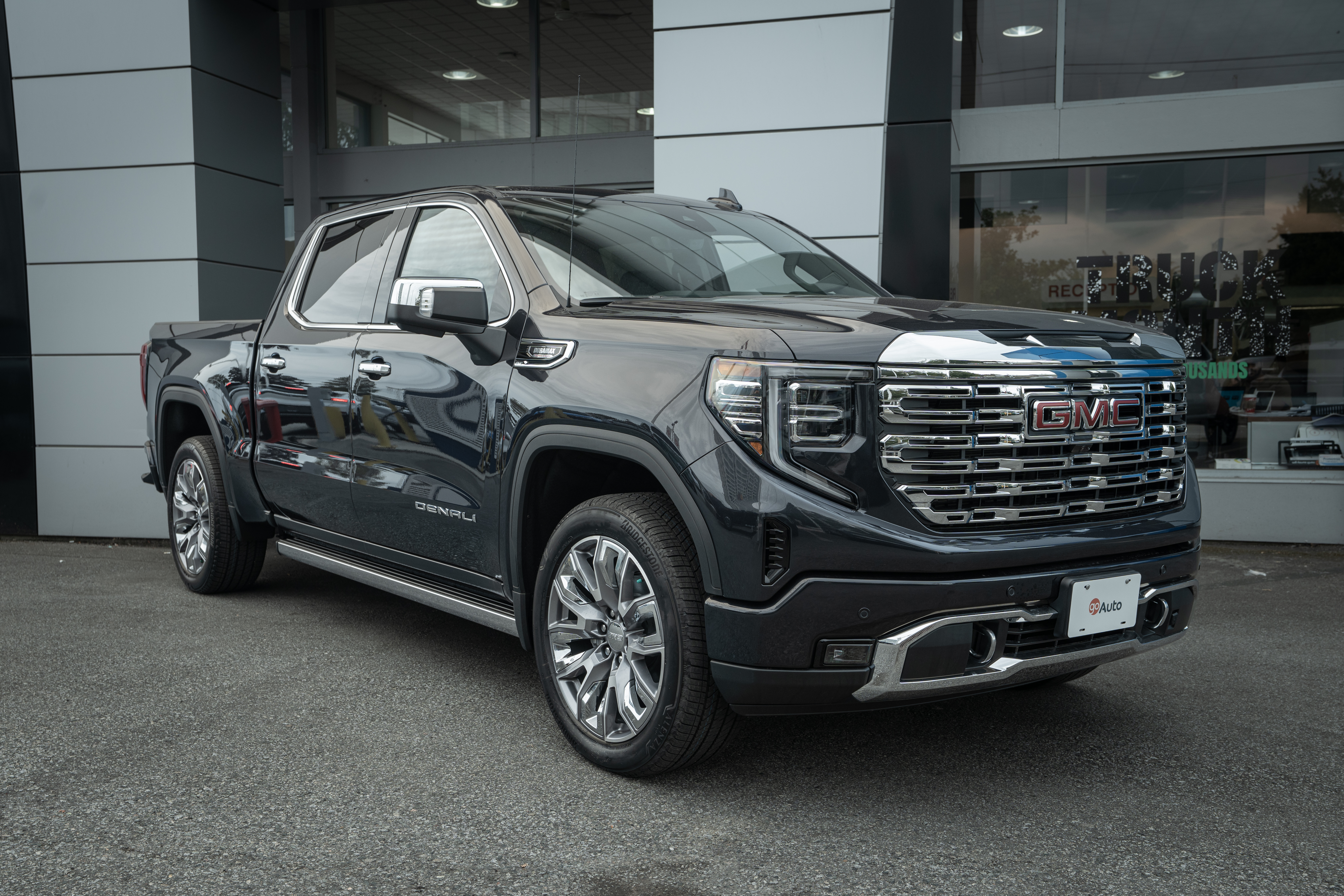 2026 GMC Sierra 1500 Denali in black parked outside dealership showroom
