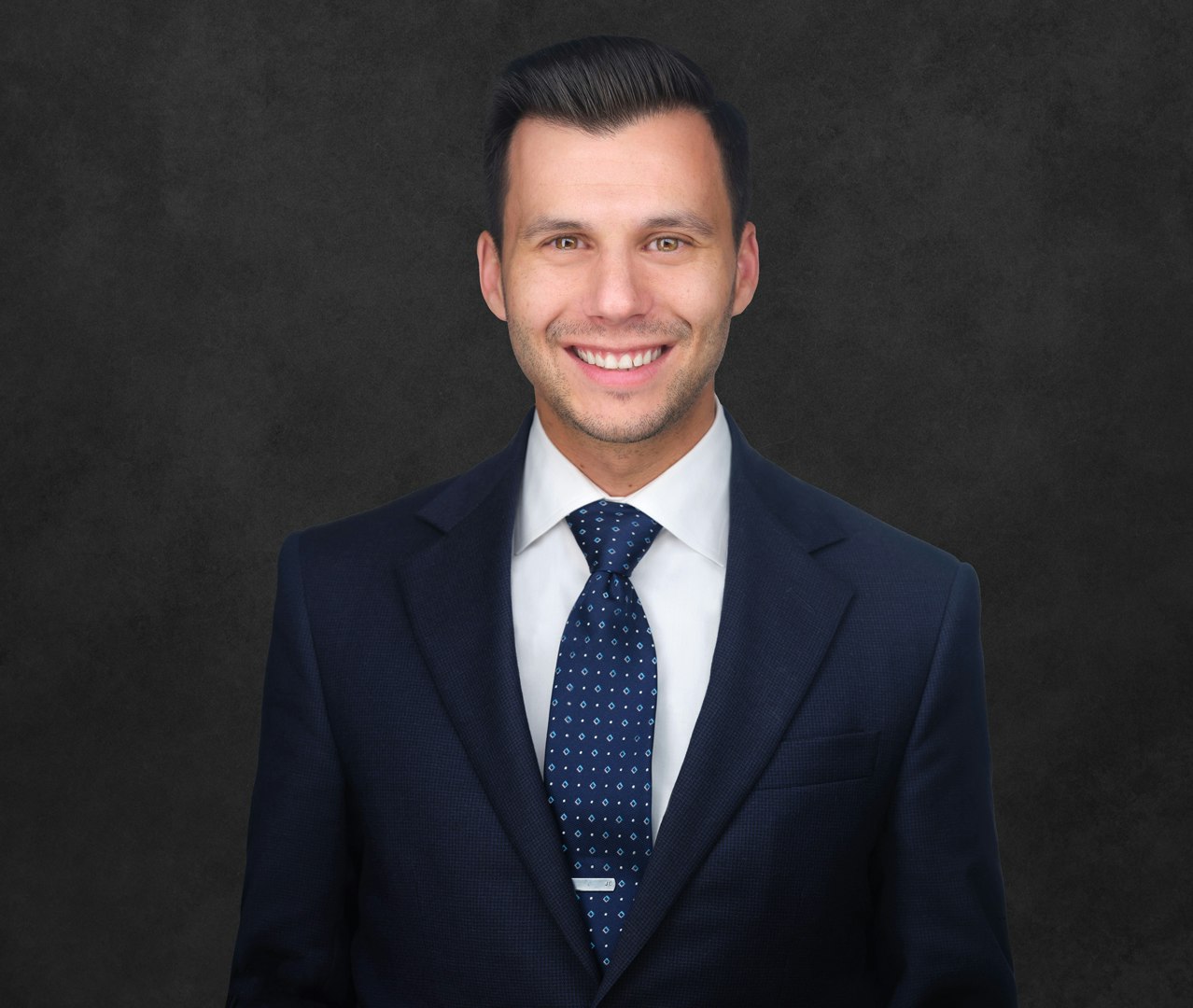 Photo of Jon Ebel smiling in suit, shirt and tie