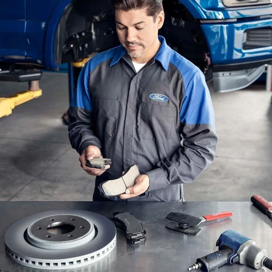 Ford service technician inspecting brake components in repair bay