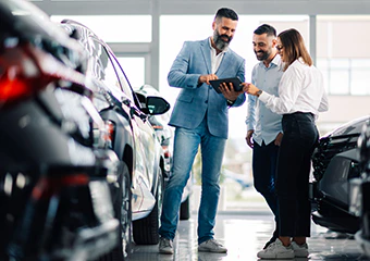 three people in a dealership excited to purchase a car