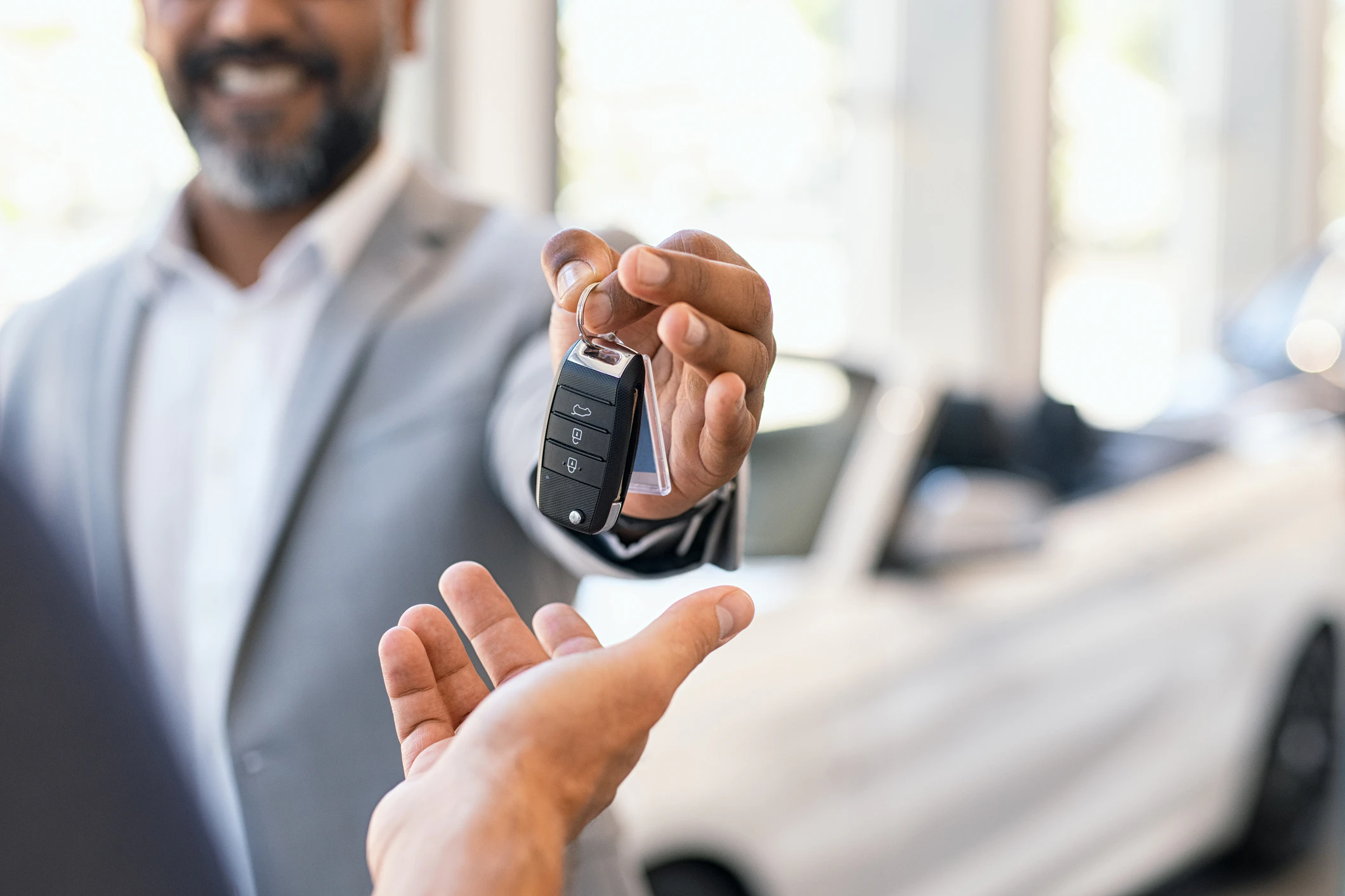 Salesman handing car keys to customer at dealership