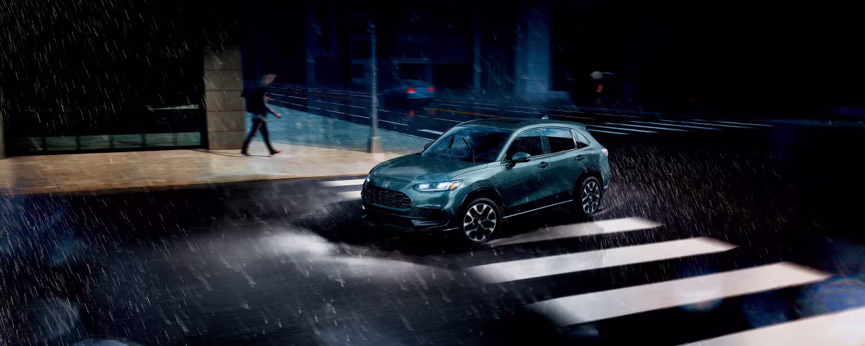 2026 Honda HR-V driving through a rainy city street.