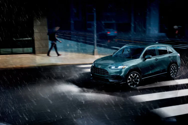 2026 Honda HR-V driving through a rainy city street.