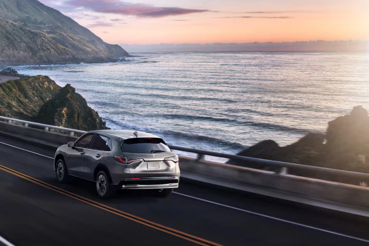 2026 Honda HR-V driving down a windy road by water.