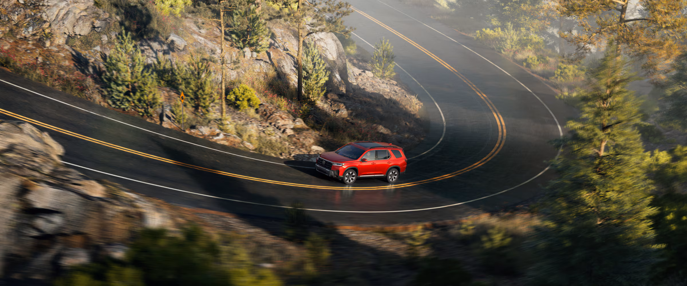 Red 2026 Honda Pilot on a windy road.
