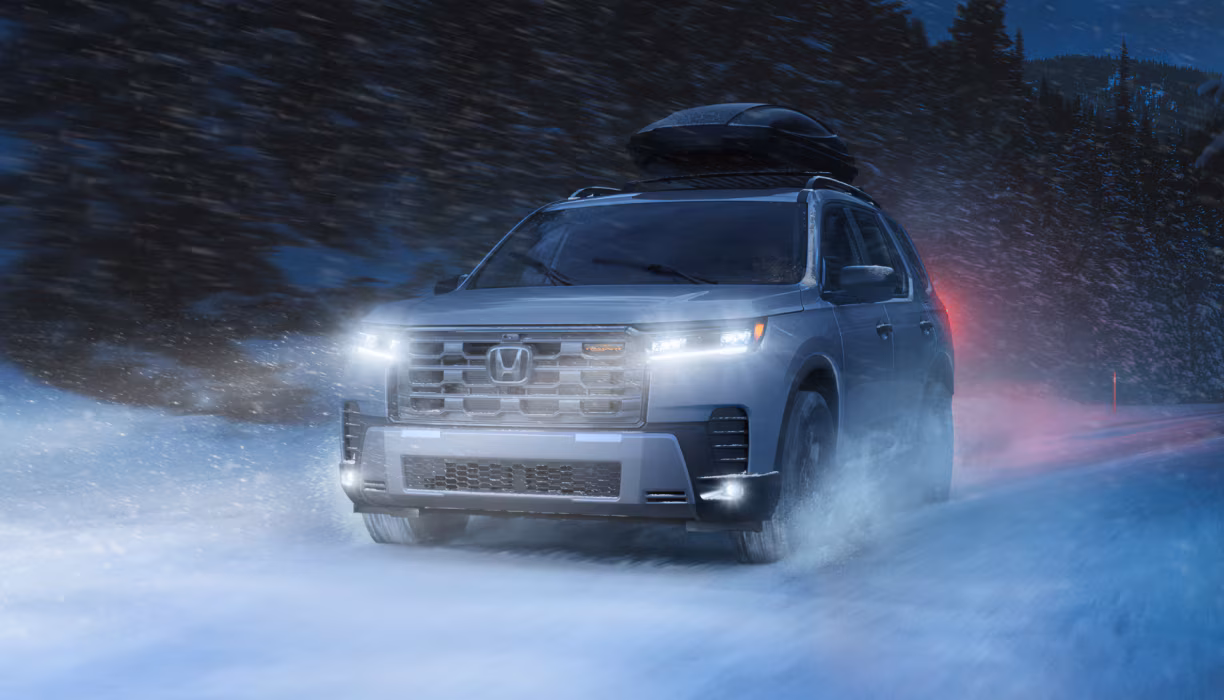 2026 Honda Pilot driving in snowy winter conditions.