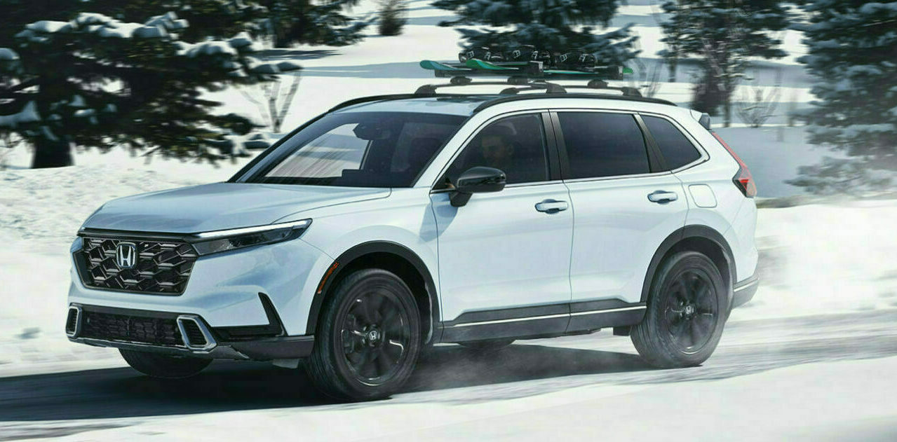 A white Honda SUV driving on the road with snow, rocks and trees in the background.