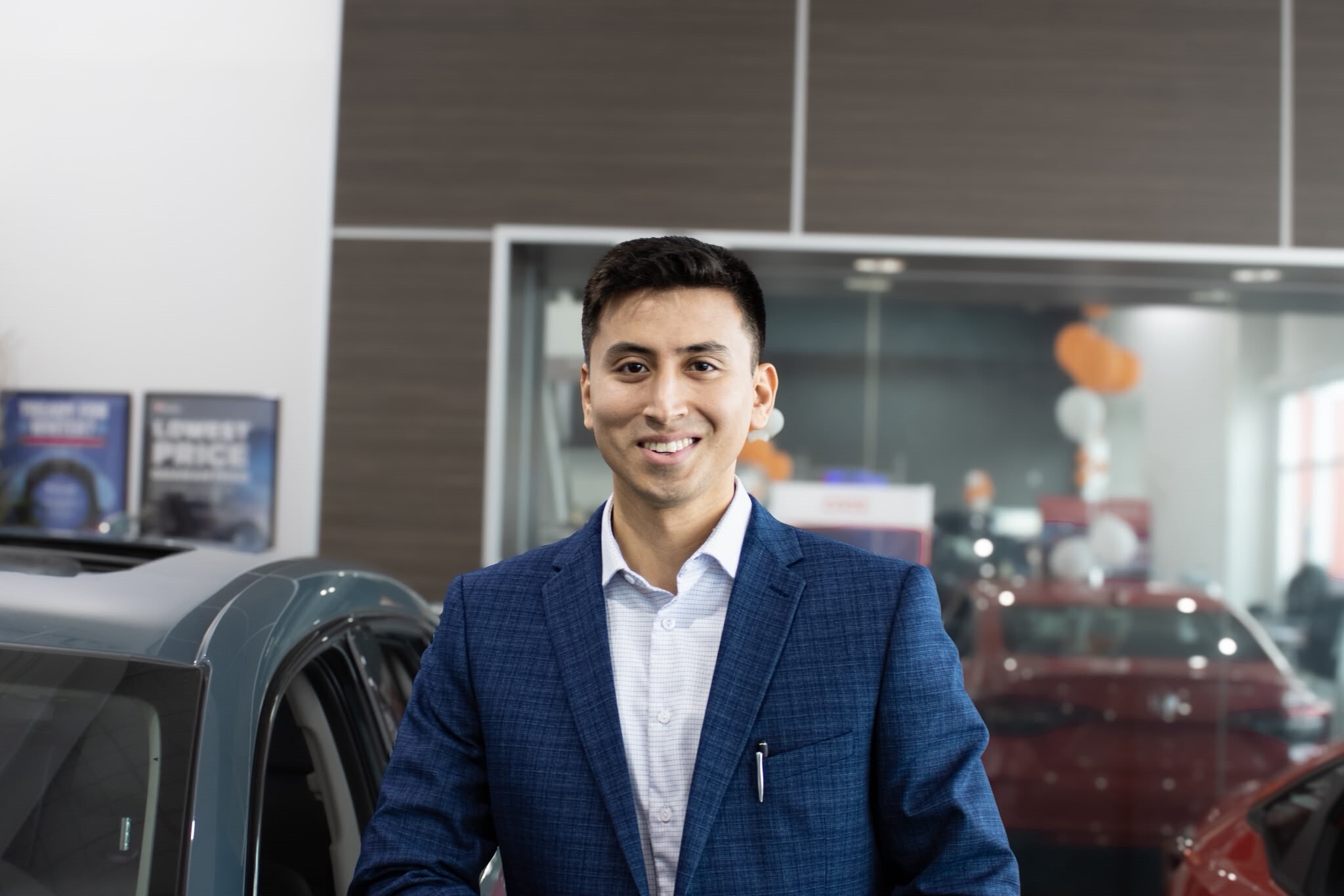 Sales representative standing in dealership showroom next to vehicle