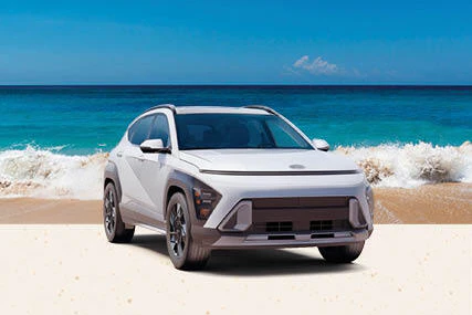 White Hyundai Kona parked on beach with ocean waves in background