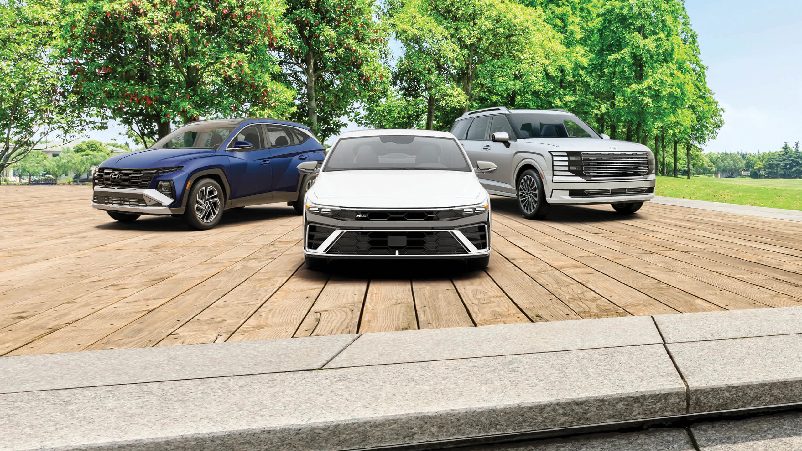 Three Hyundai vehicles displayed on wooden platform with tree-lined background