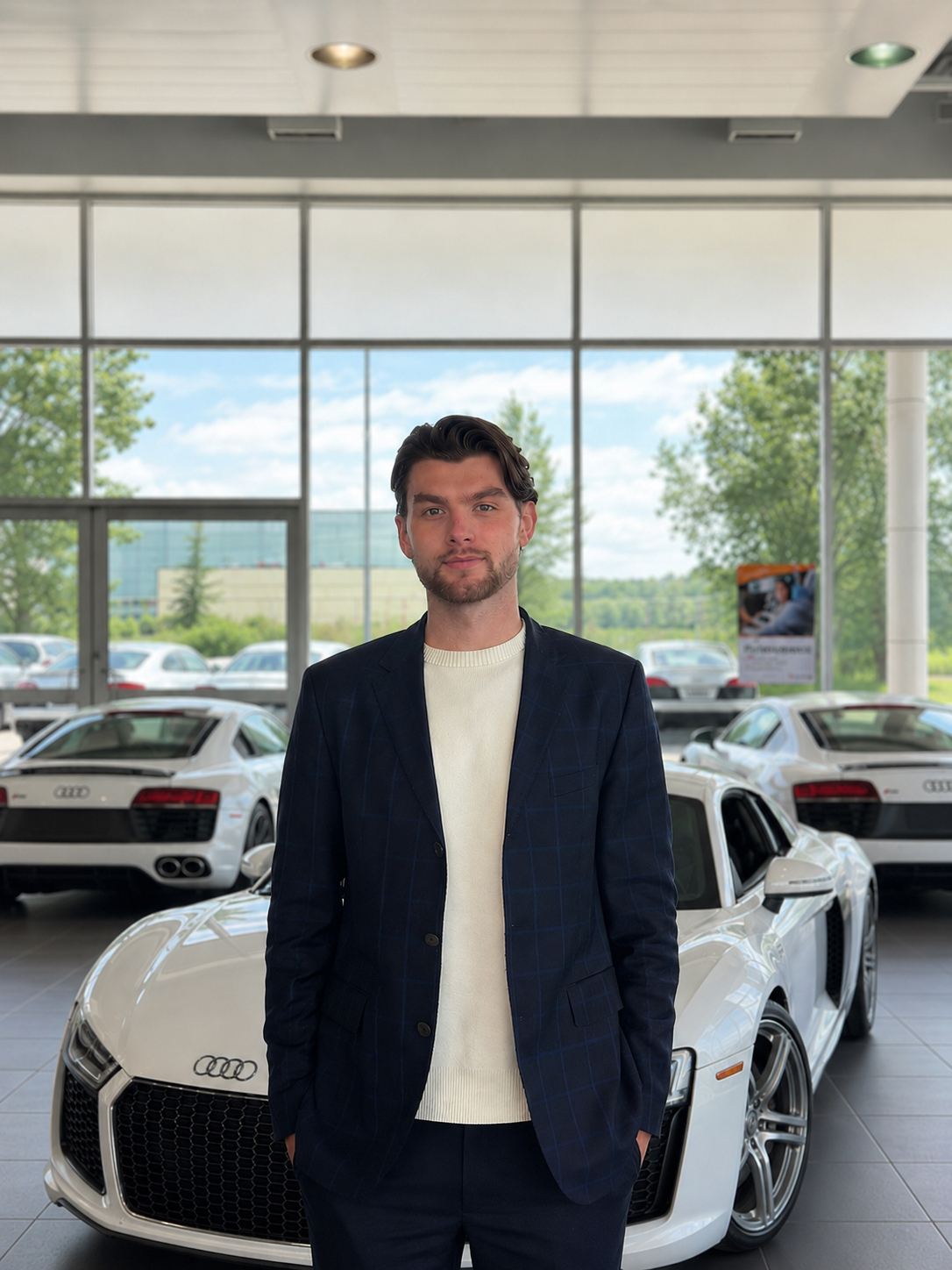 Salesman standing in front of white Audi sports car in dealership showroom