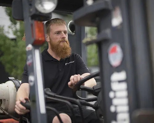 A man with a beard is driving a forklift truck