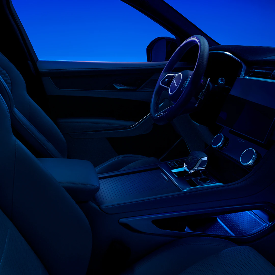 Modern car interior with steering wheel, dashboard, and blue ambient lighting