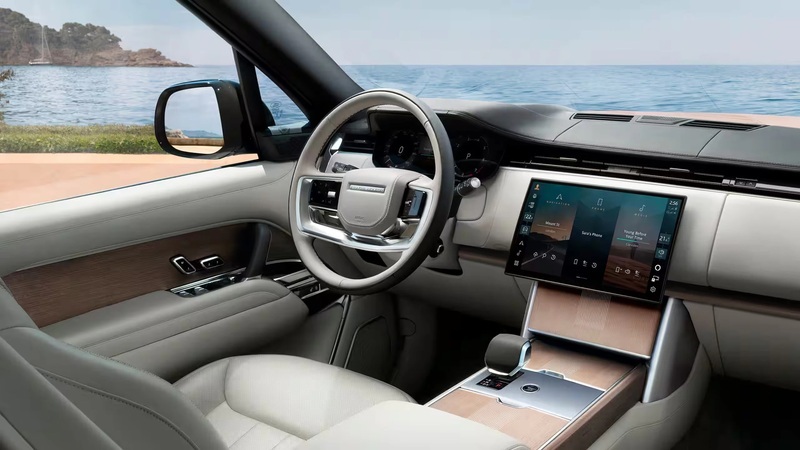 Land Rover interior with touchscreen display and steering wheel overlooking ocean coastline