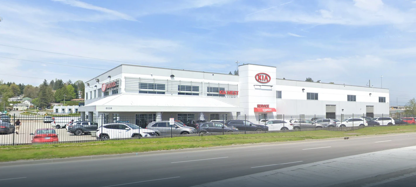 Kia dealership building with inventory of vehicles parked in front lot
