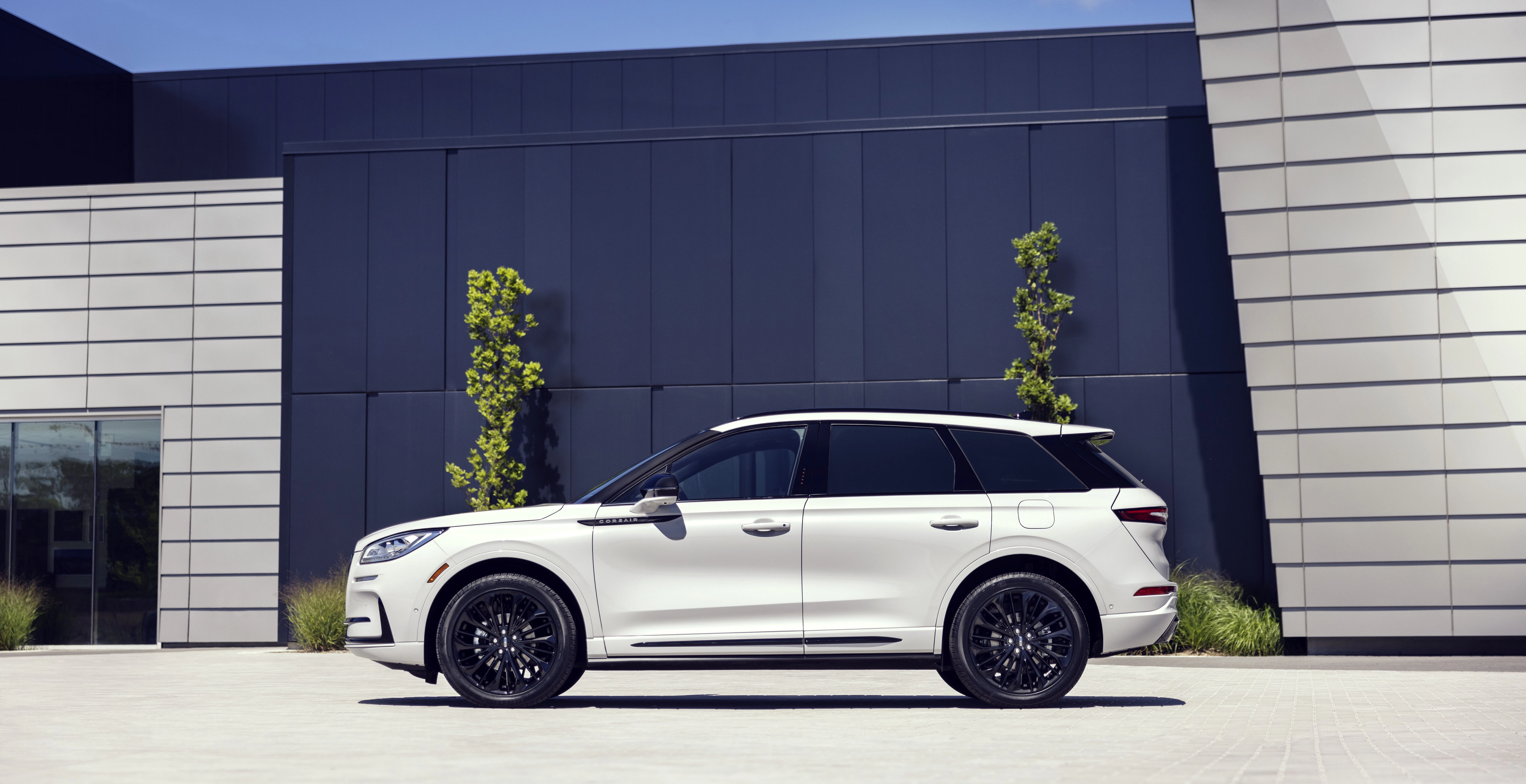 White luxury SUV parked in front of modern dealership building with dark paneling