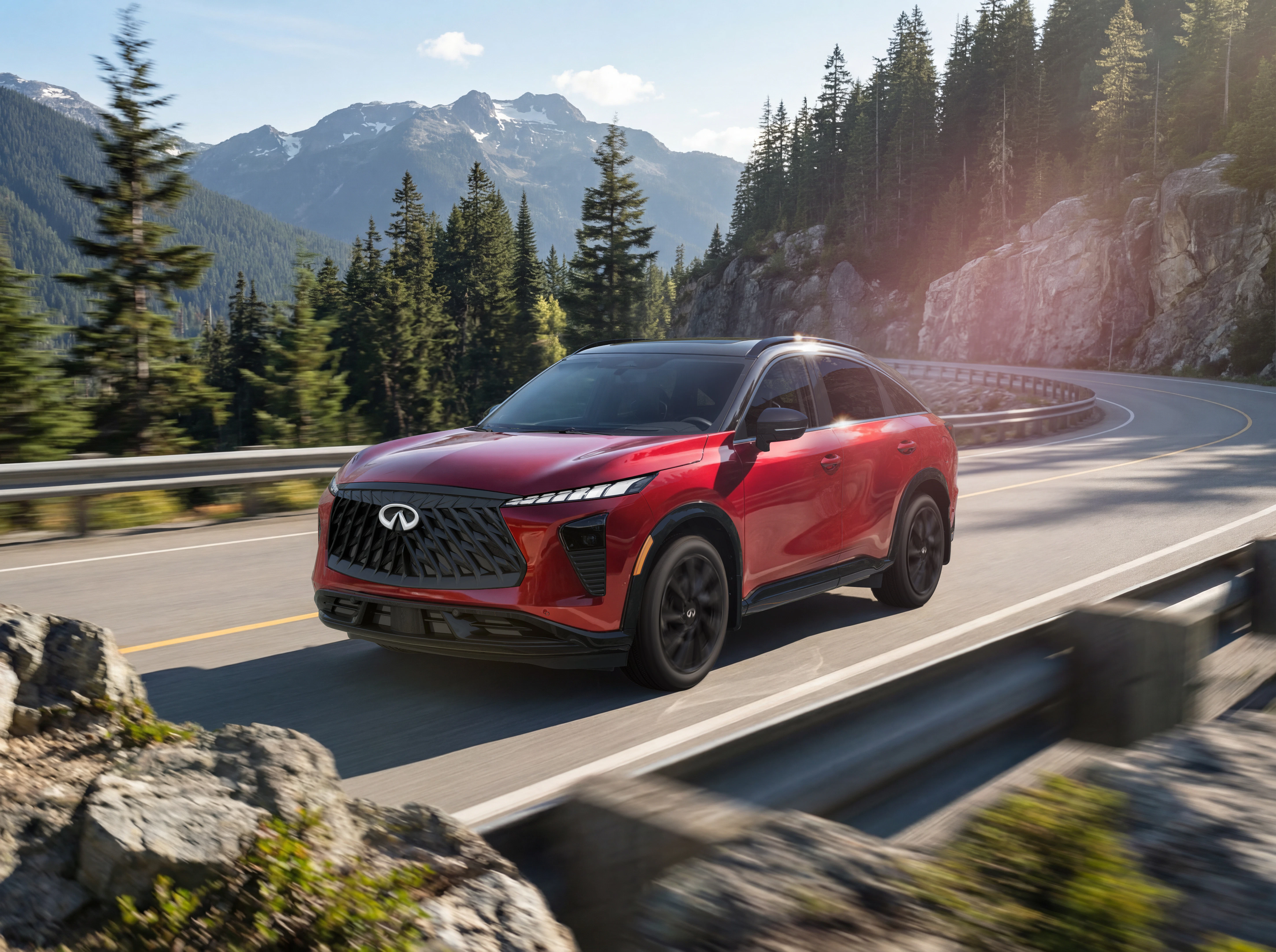 Red Infiniti QX65 driving on mountain highway with forest and peaks in background
