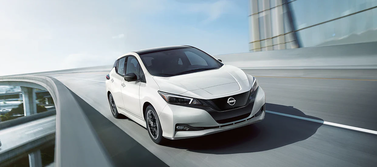 2023 Nissan Leaf electric vehicle driving on modern highway overpass