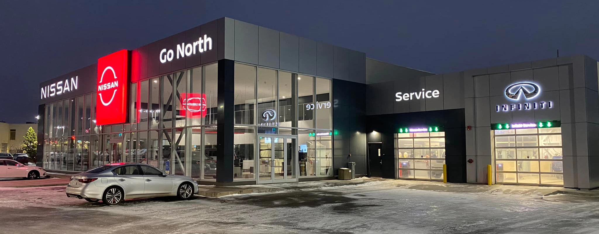 Go North Nissan dealership storefront at night with illuminated signage and service bay