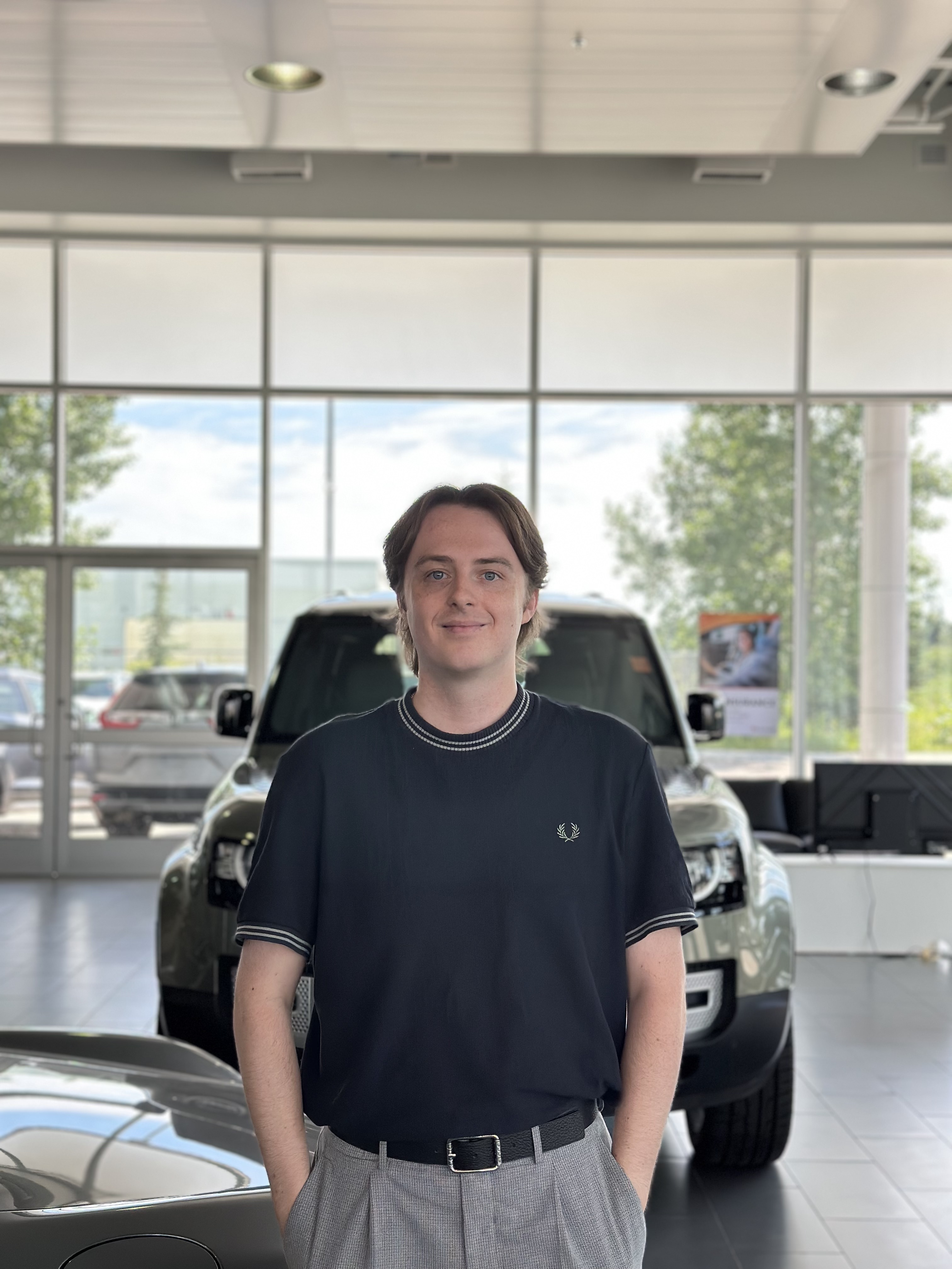 Go Auto dealership staff member standing in showroom with vehicles displayed behind him