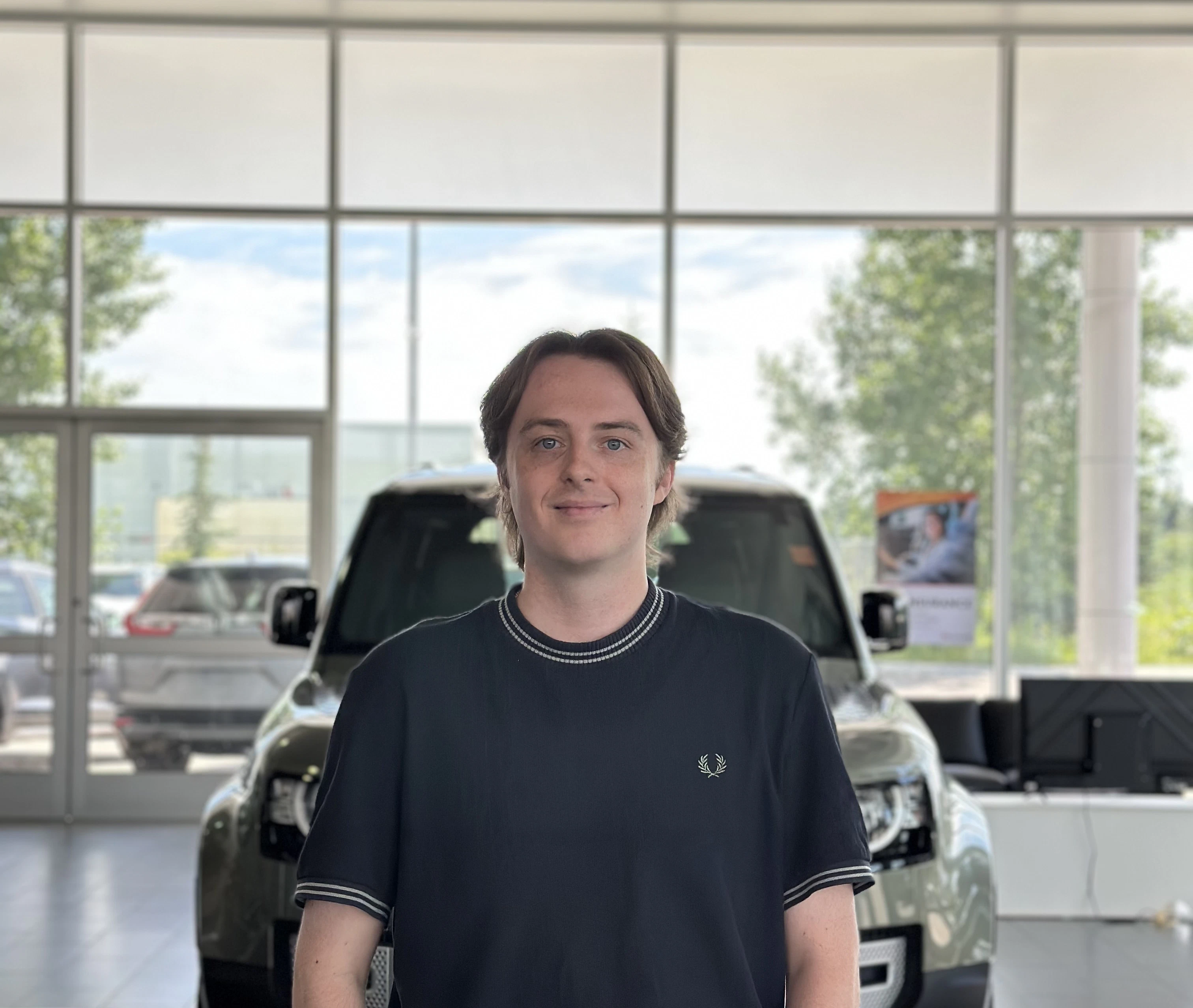 Go Auto dealership staff member standing in showroom with vehicles displayed behind him