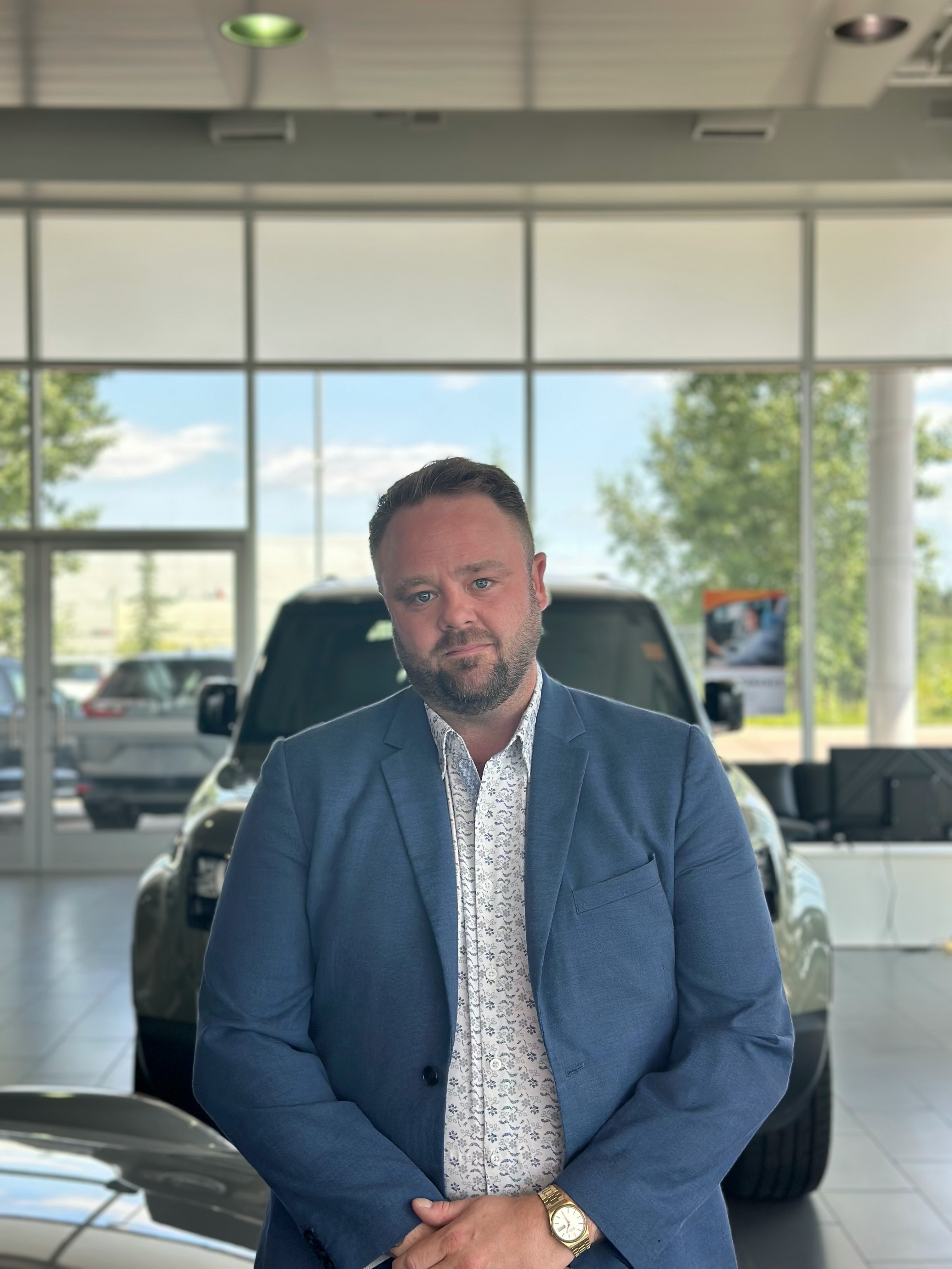 Go Auto dealership sales professional in showroom with vehicles visible through windows behind him