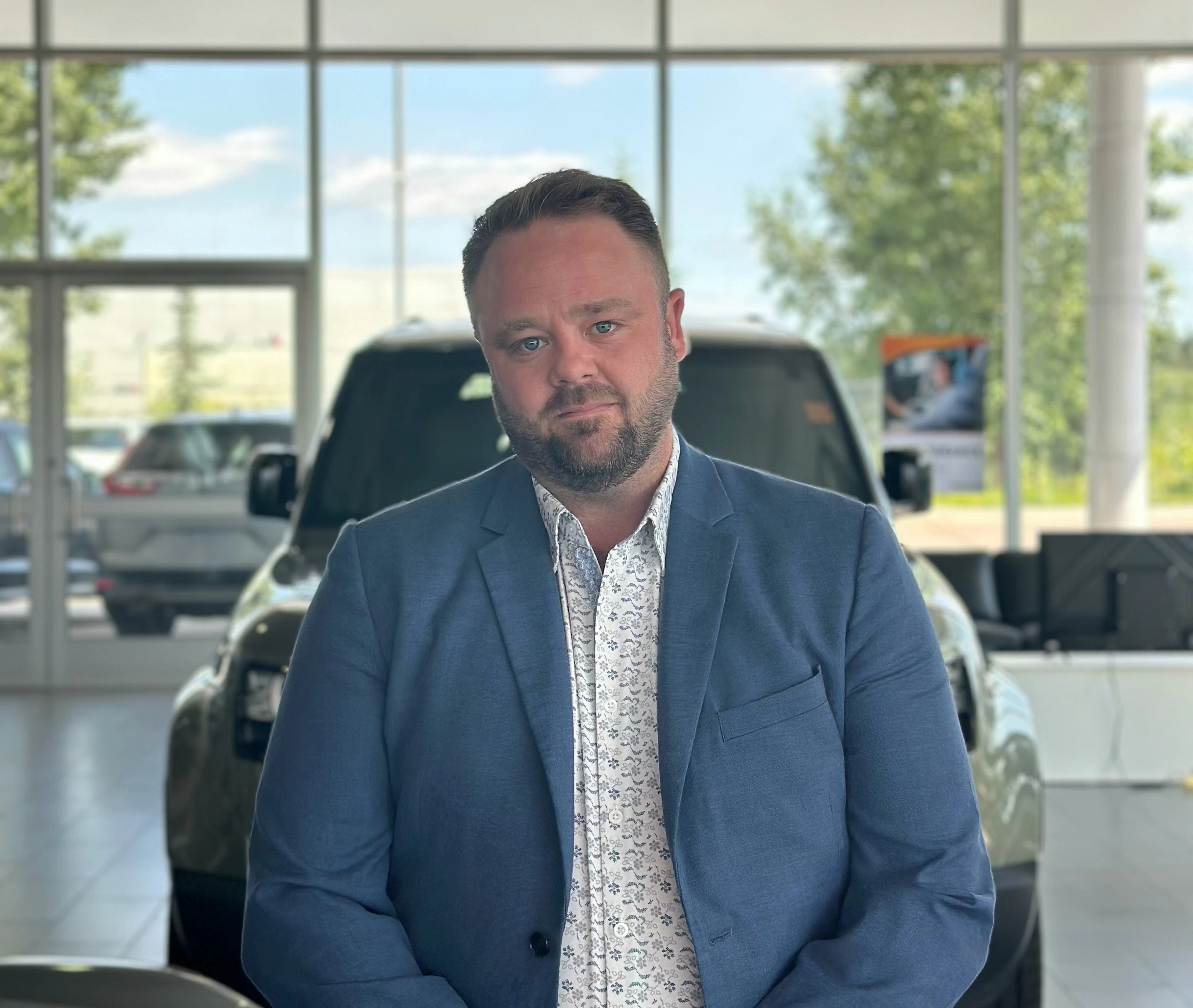 Go Auto dealership sales professional in showroom with vehicles visible through windows behind him