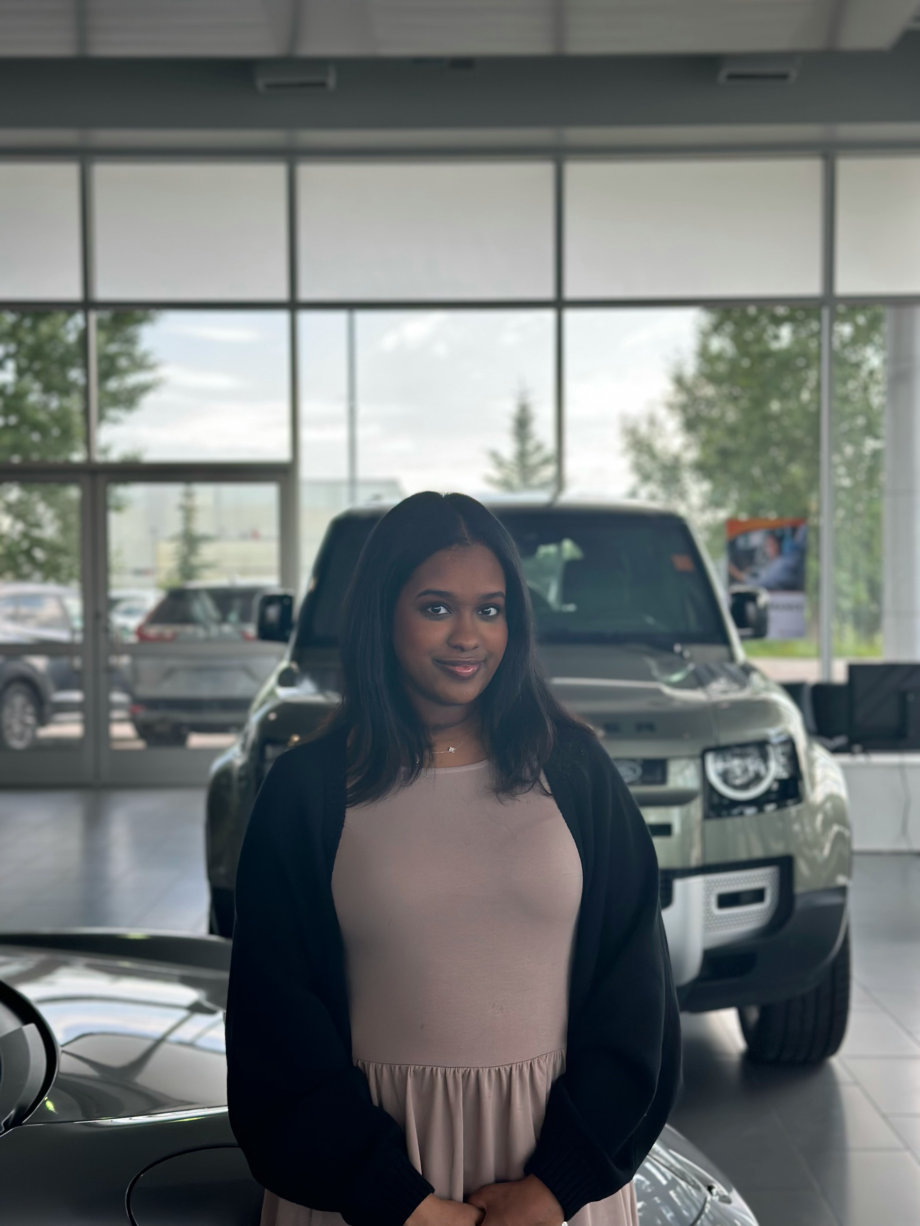 Woman smiling in dealership showroom with vehicles visible through large windows