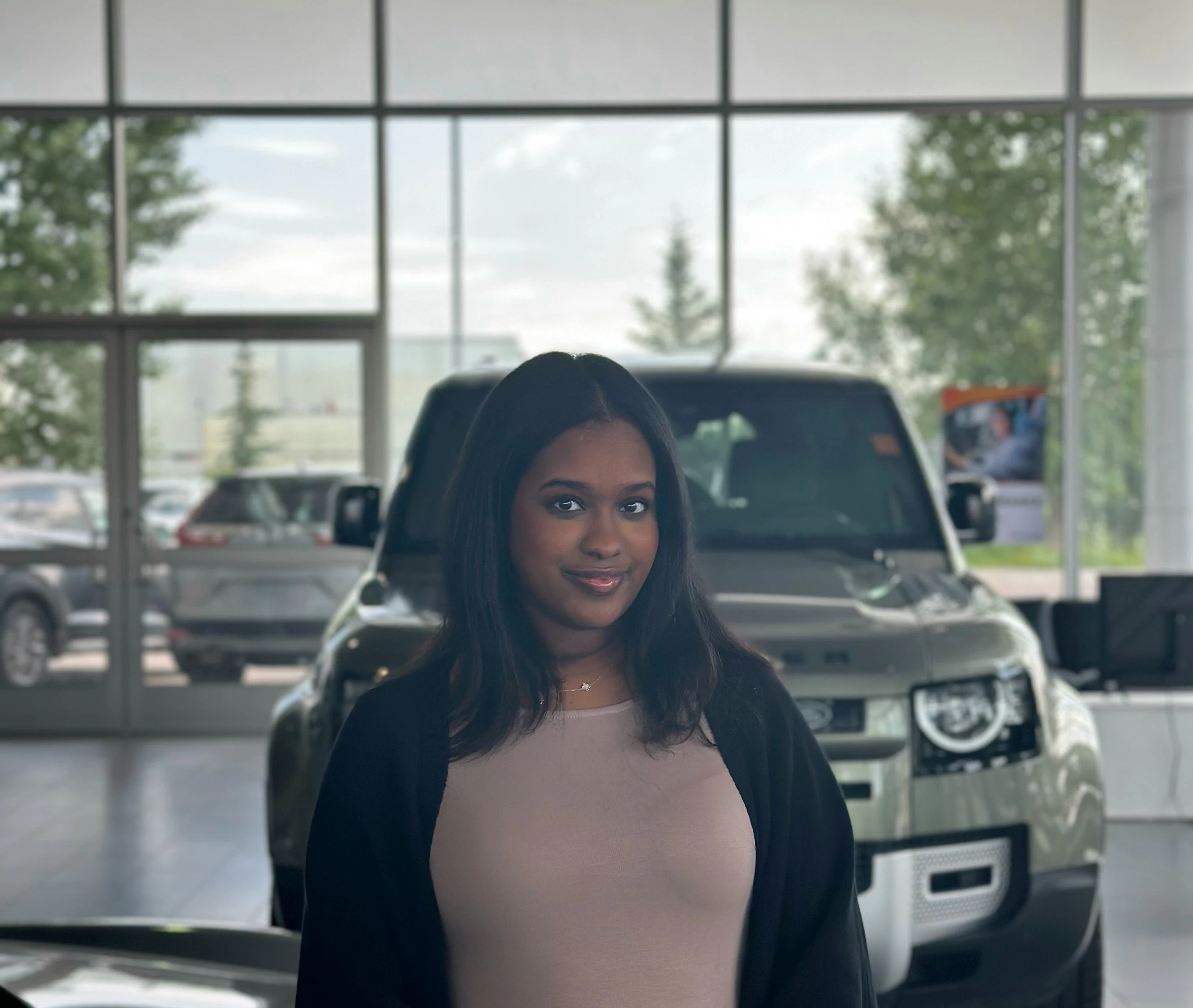 Woman smiling in dealership showroom with vehicles visible through large windows