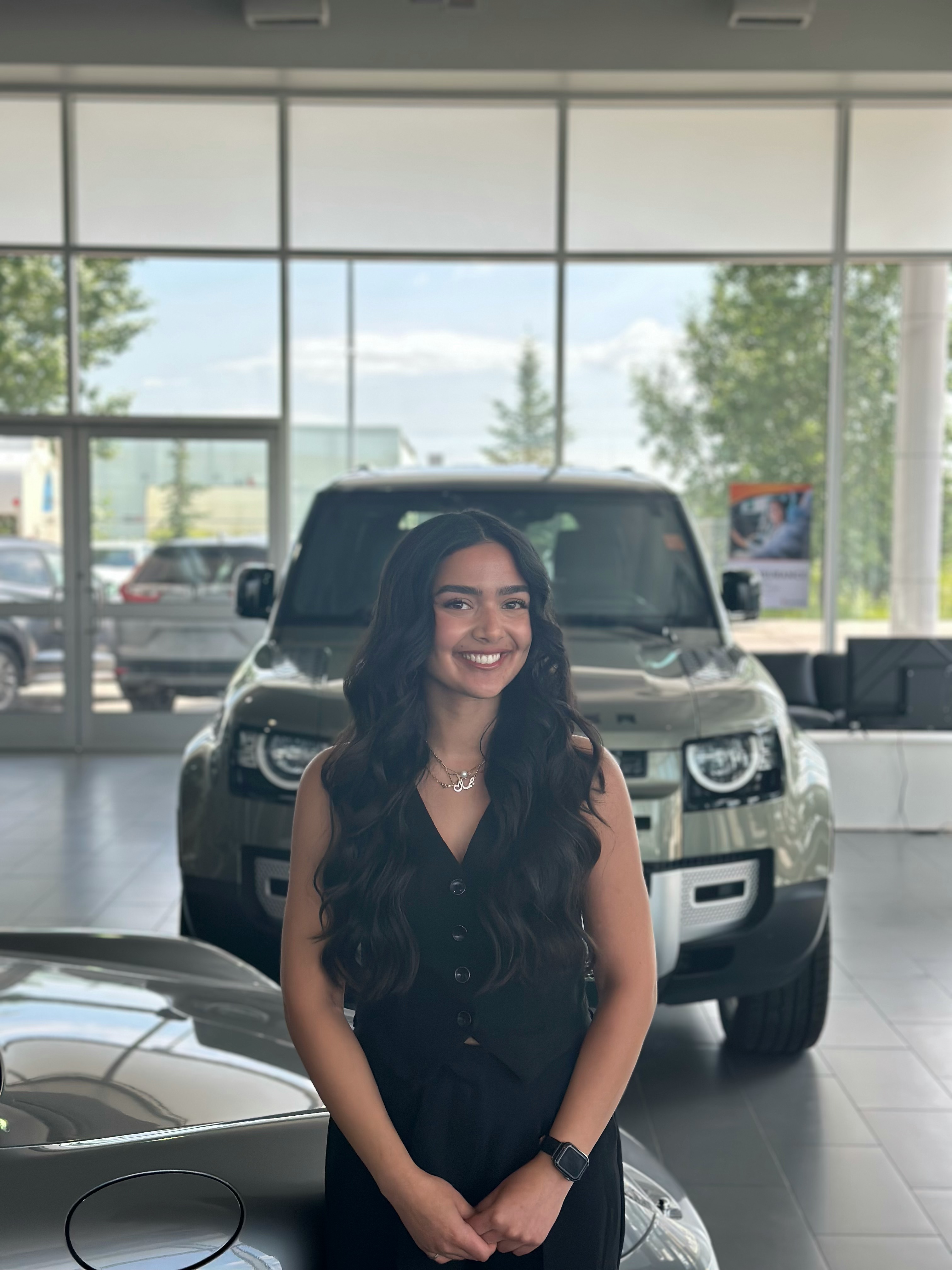 Go Auto sales associate standing in dealership showroom with vehicles in background