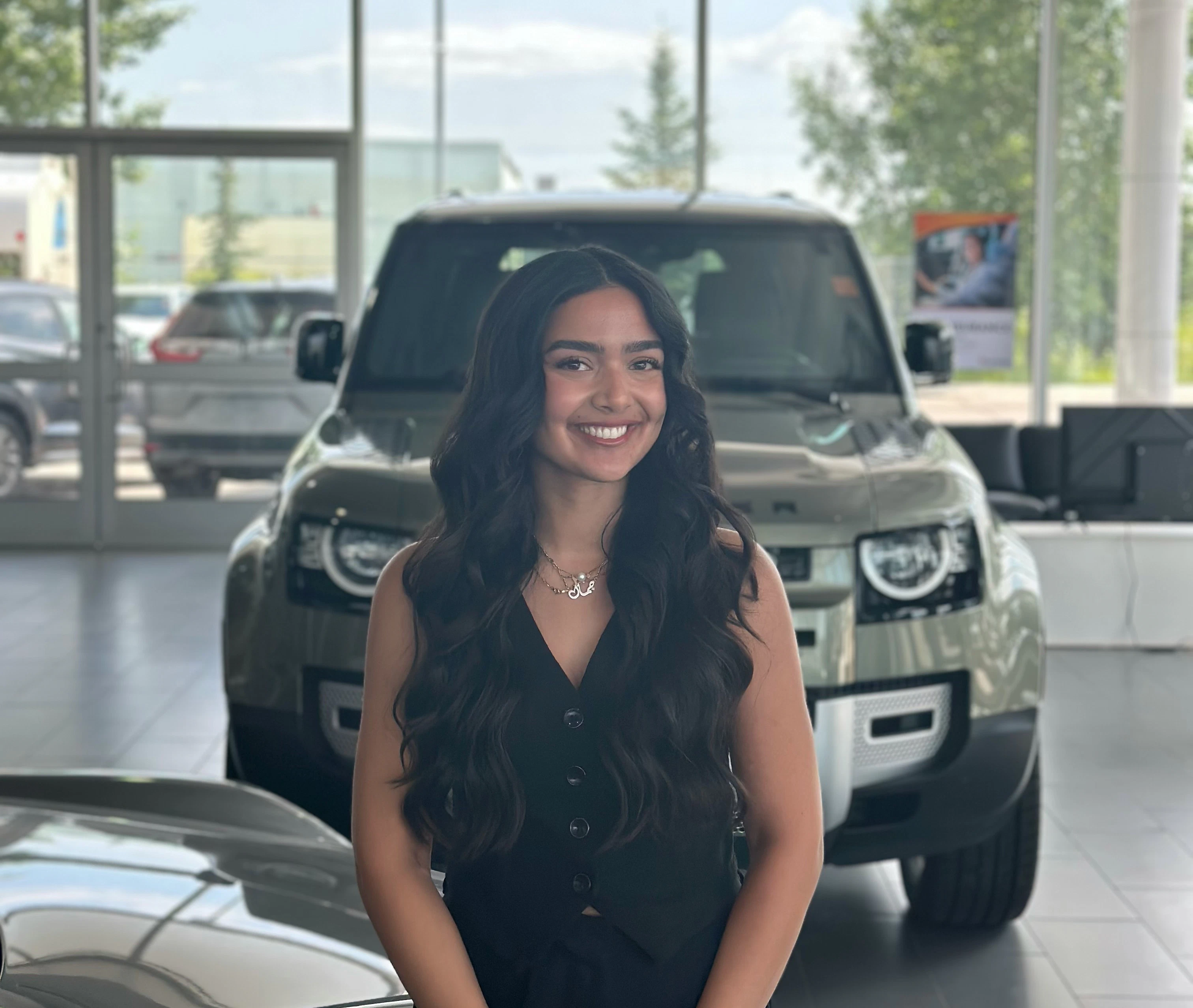 Go Auto sales associate standing in dealership showroom with vehicles in background