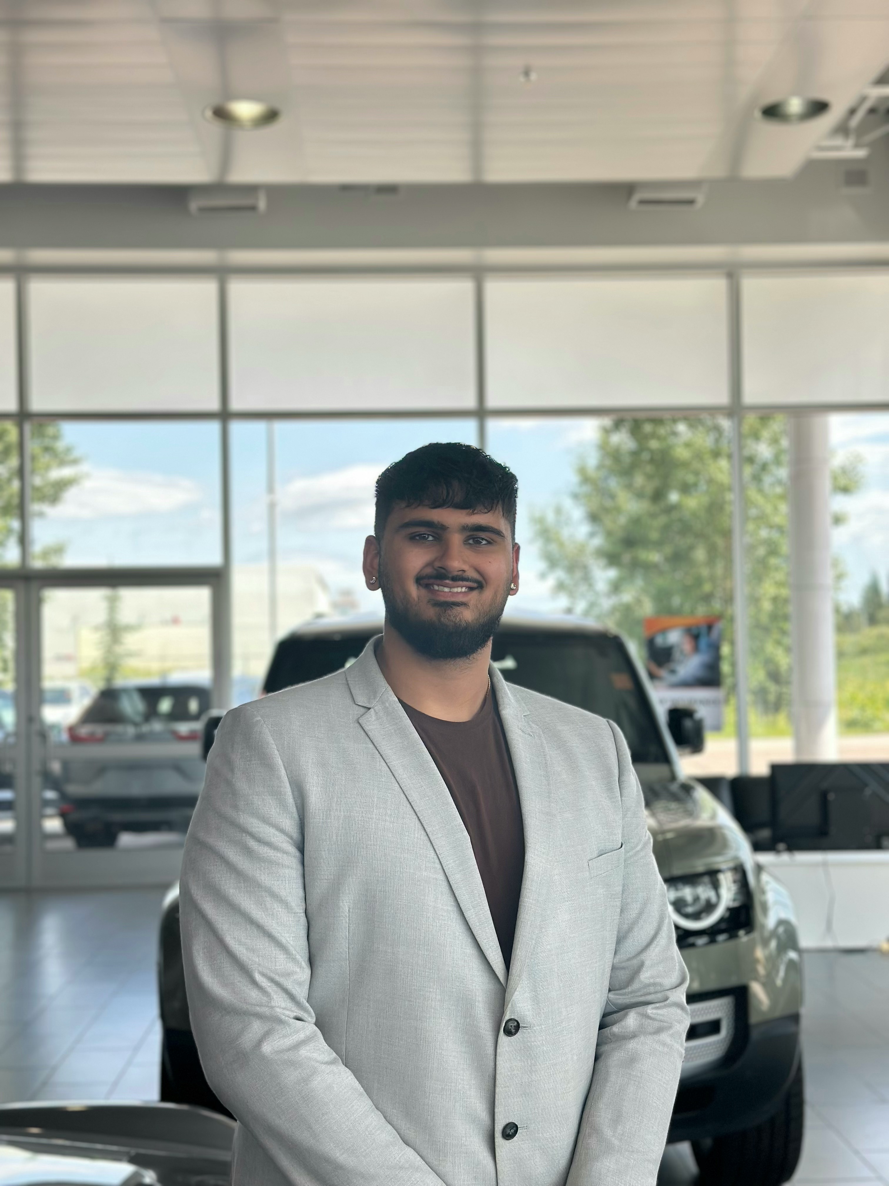 Sales associate posing in dealership showroom with vehicles in background