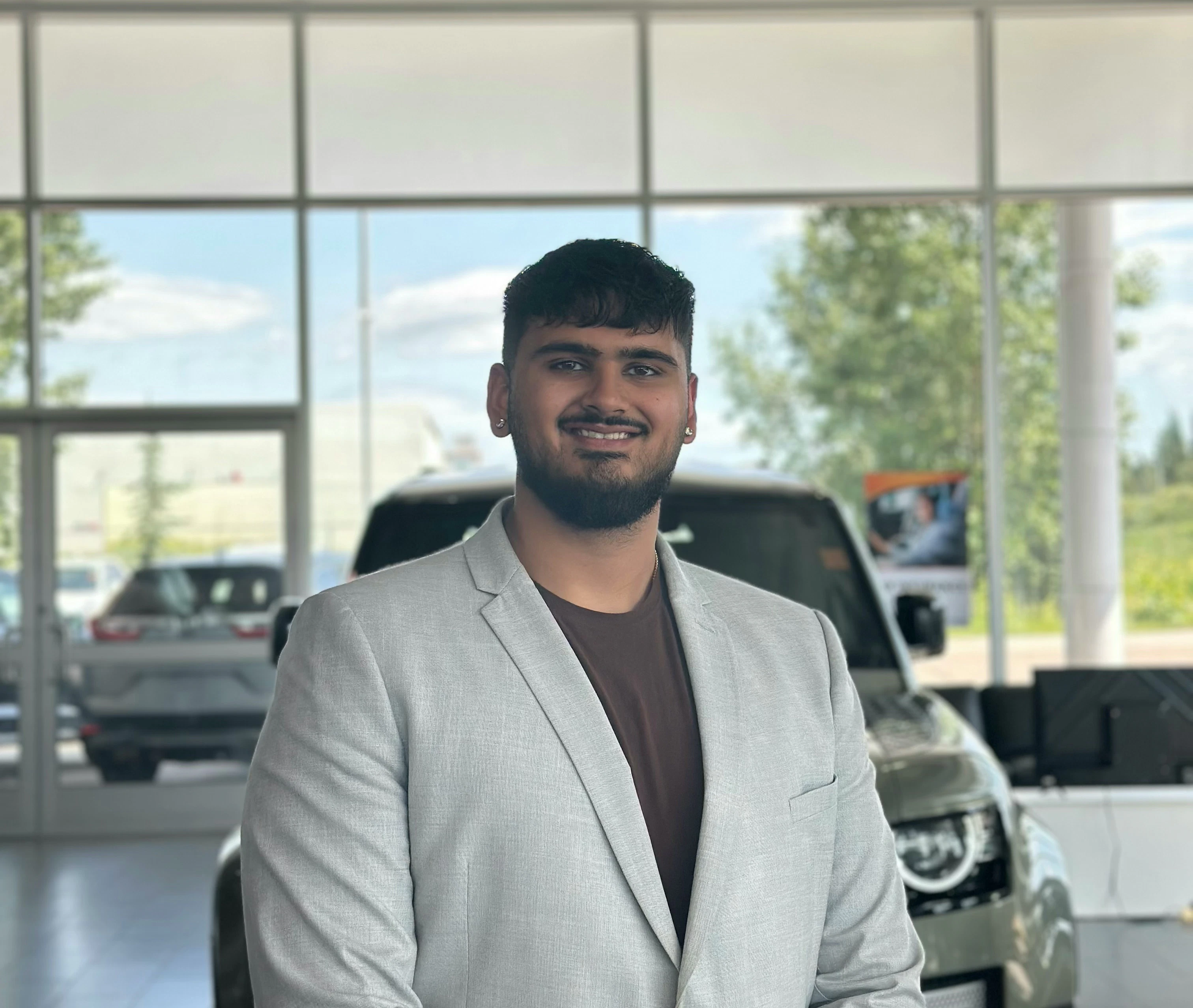 Sales associate posing in dealership showroom with vehicles in background