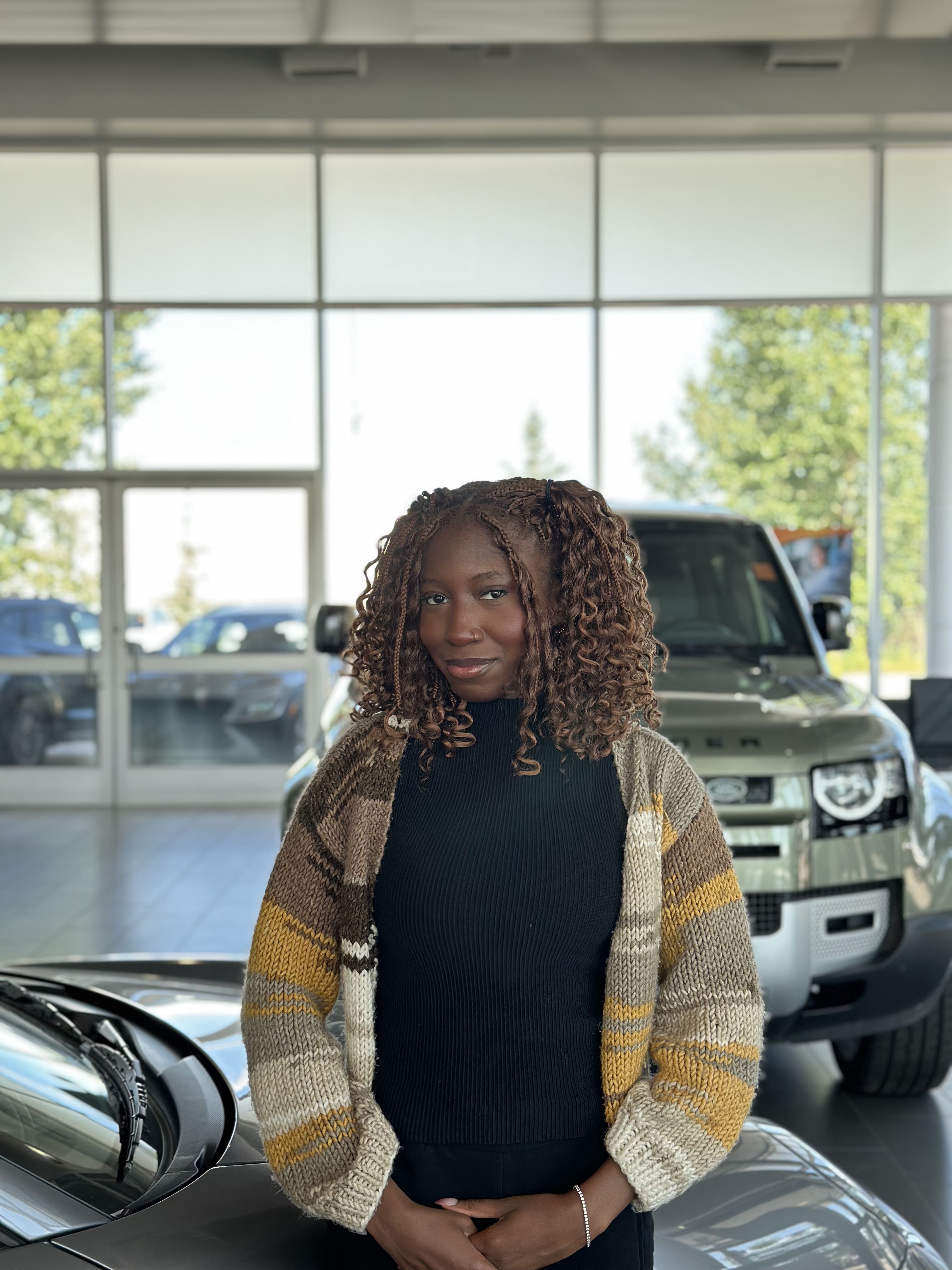 Customer posing in Go Auto dealership showroom with vehicles in background