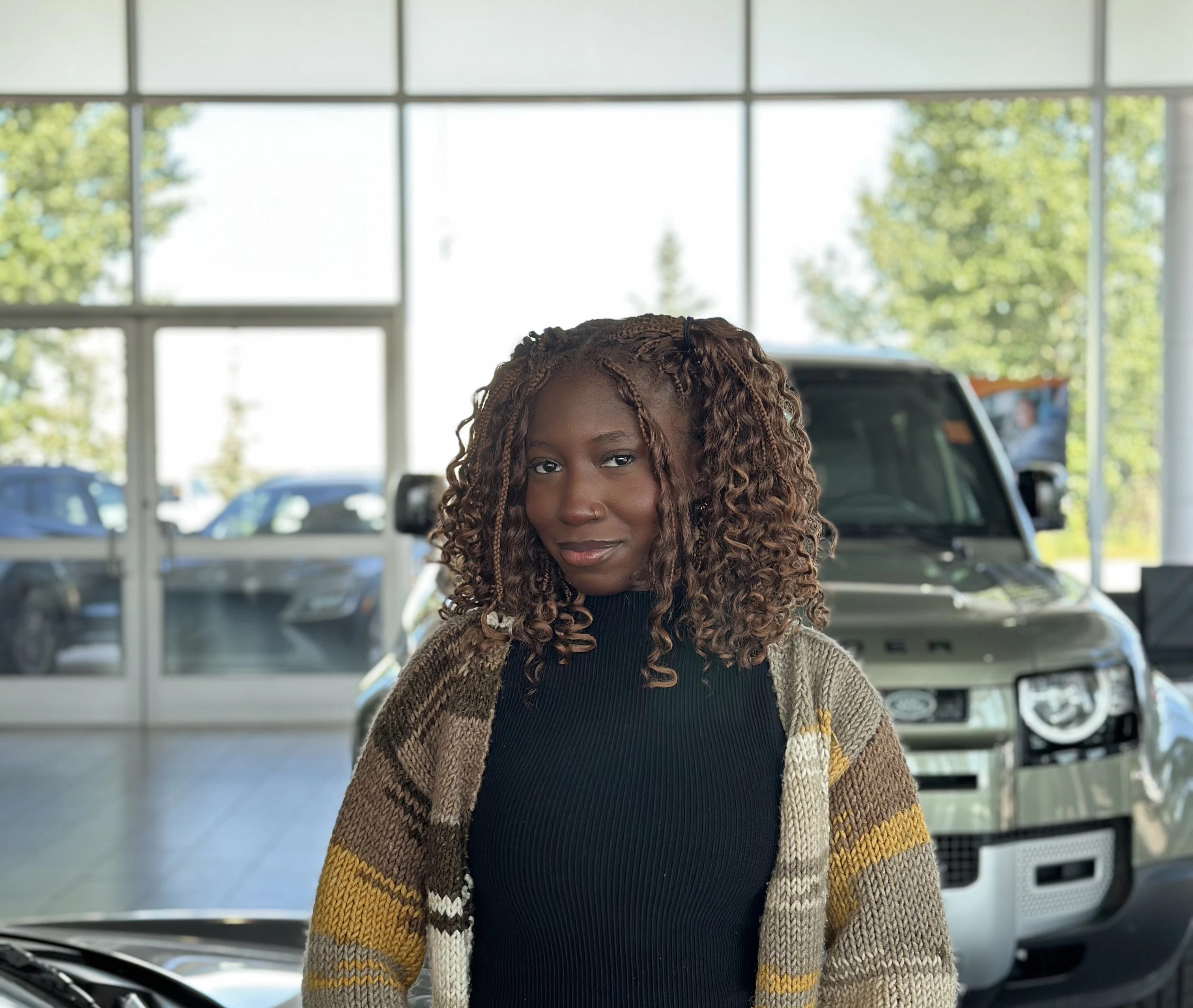 Customer posing in Go Auto dealership showroom with vehicles in background
