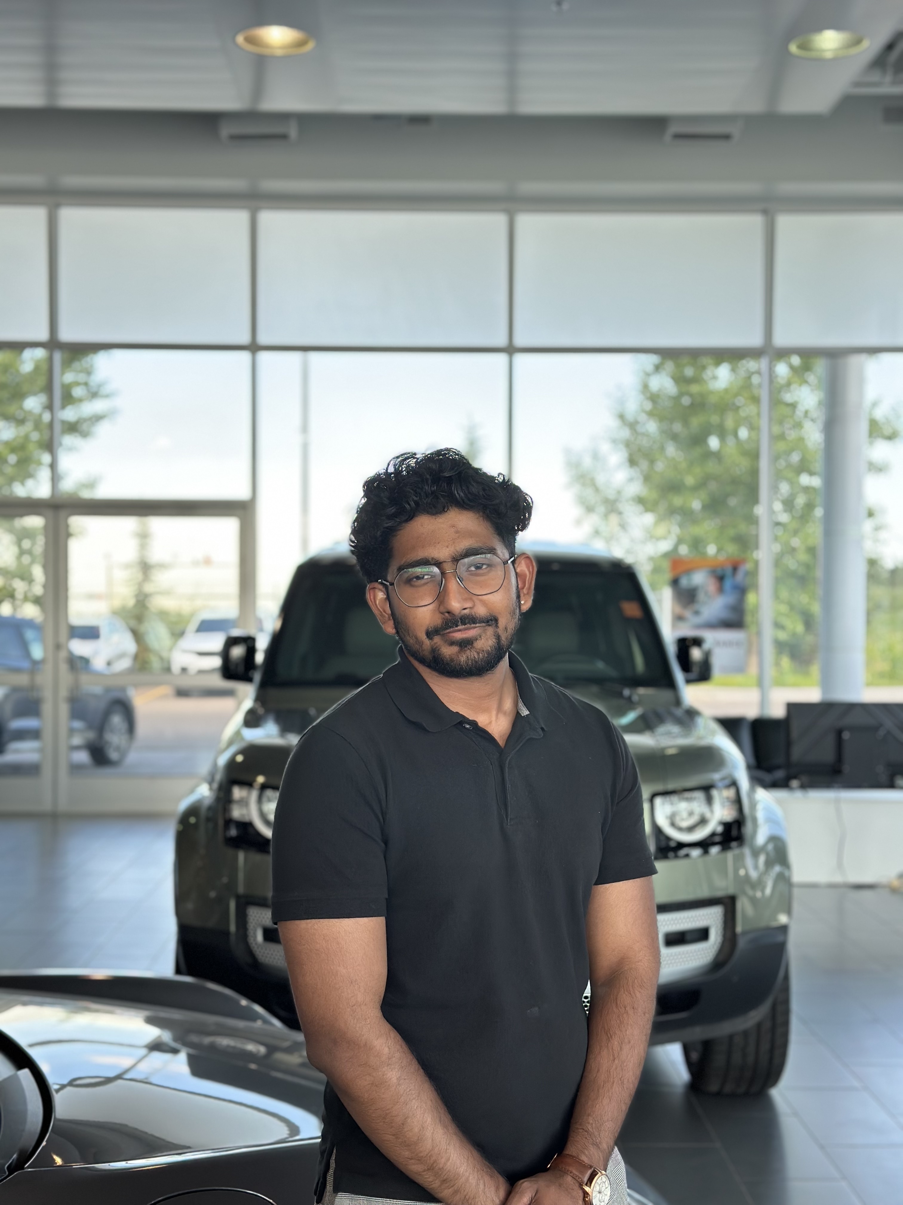 Sales representative standing in Go Auto dealership showroom with vehicles displayed behind him
