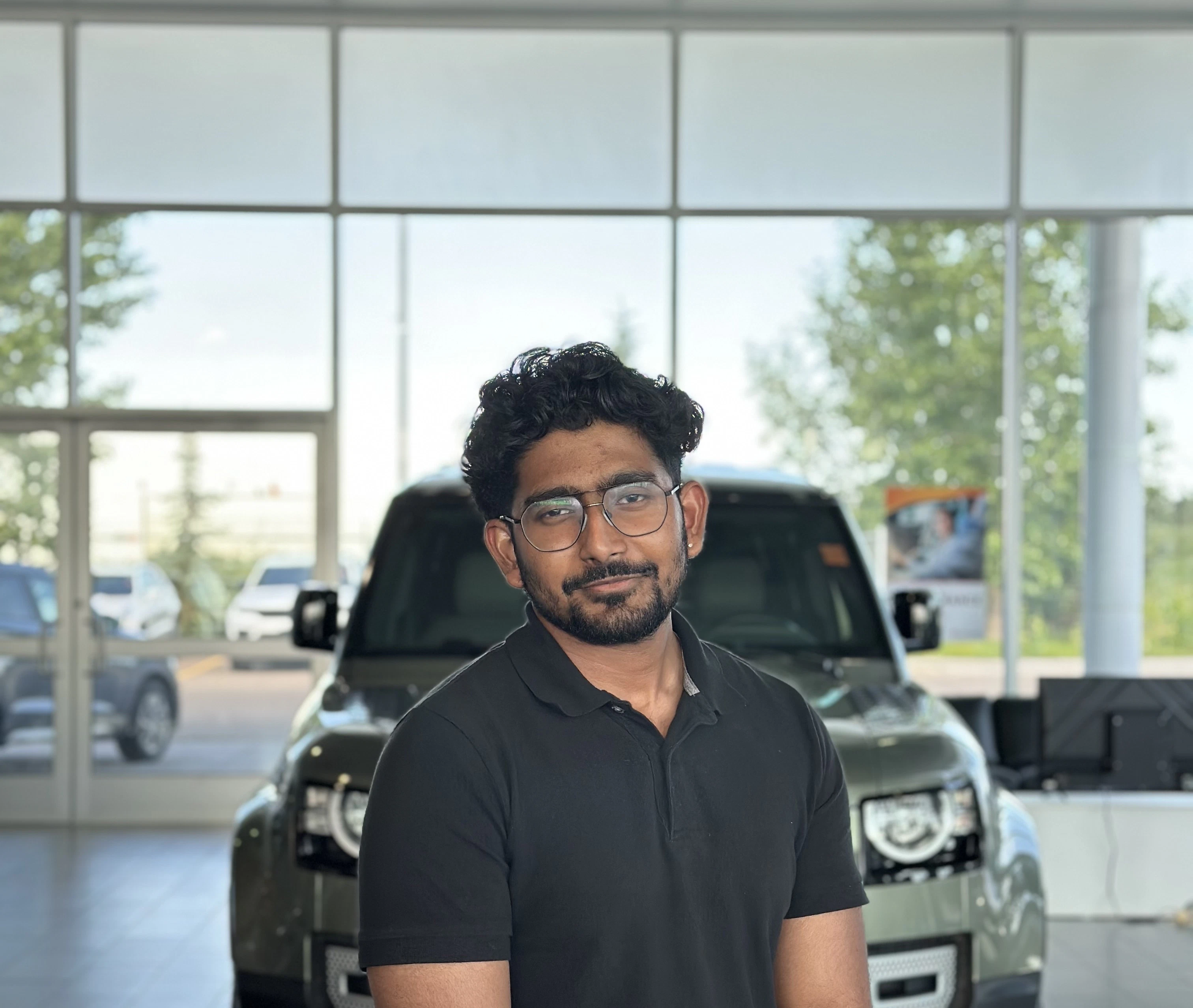 Sales representative standing in Go Auto dealership showroom with vehicles displayed behind him