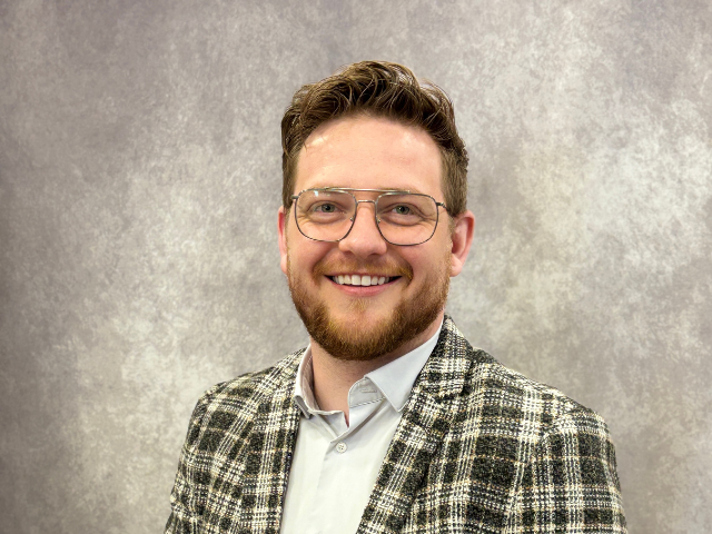 Jordan Harding, Go Auto sales representative, smiling at camera in plaid blazer