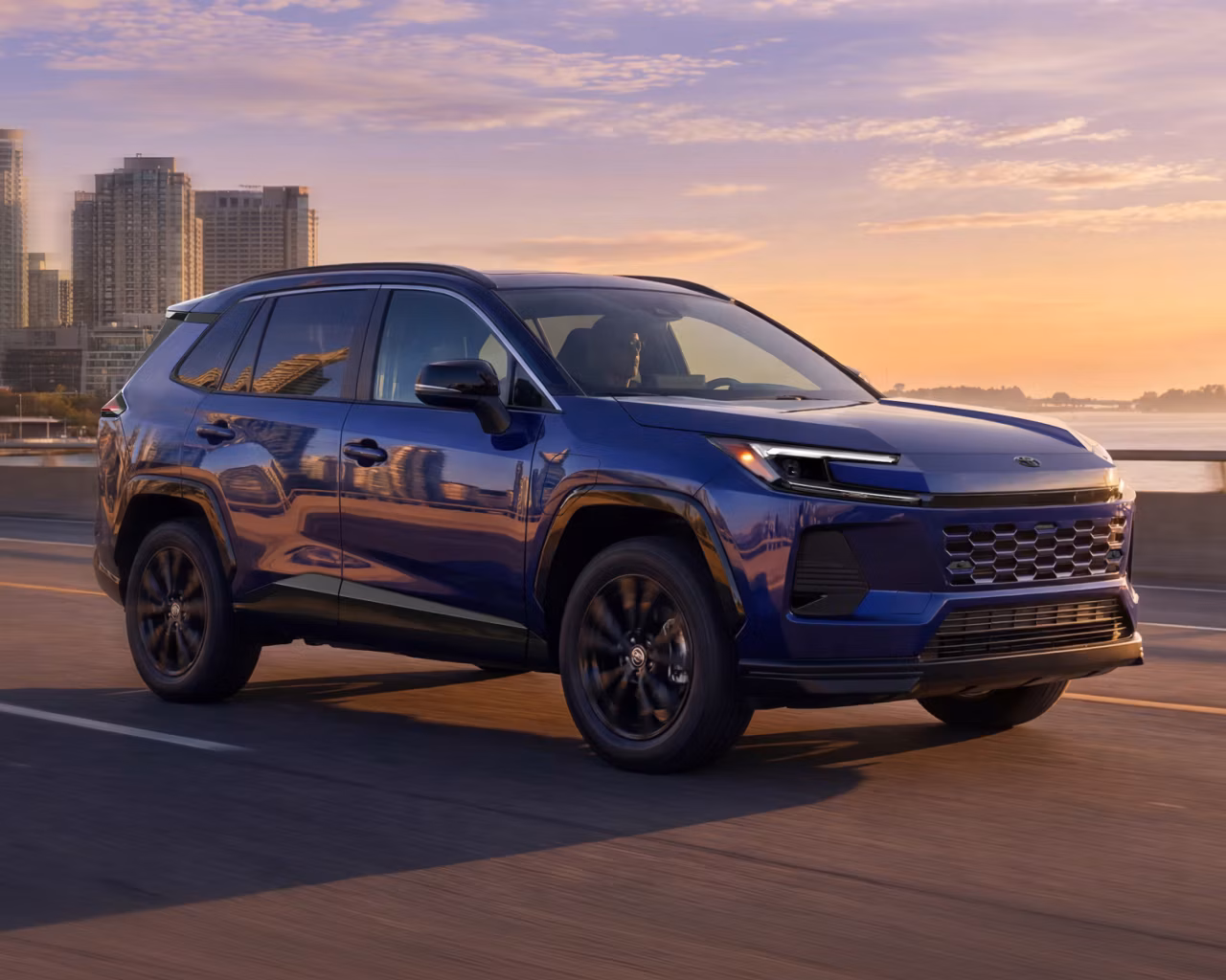 Toyota 2026 RAV4 Plug-In Hybrid driving in the city at sunset
